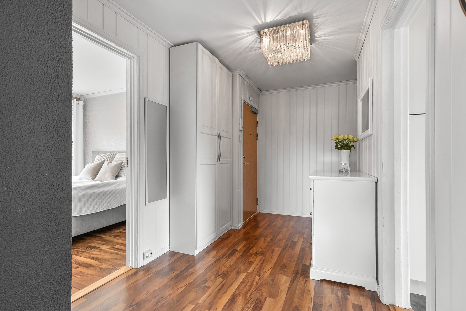 Romslig entré med laminat på gulv, panel på vegger og slett flate i himling. Det er god plass til garderobeskap for praktisk oppbevaring av yttertøy og sko Galleribilde