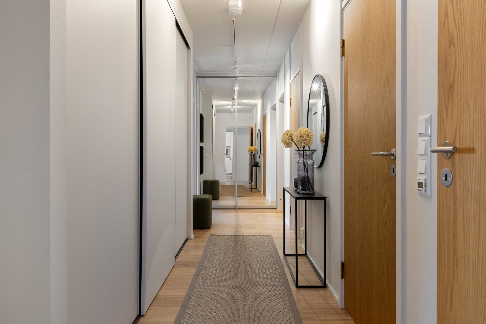 Entreen er innbydende med slette veggflater og dører i tre som mykner opp. Ved døren er det takhøy, plassbygd skyvedørsgarderobe med speilfronter Galleribilde