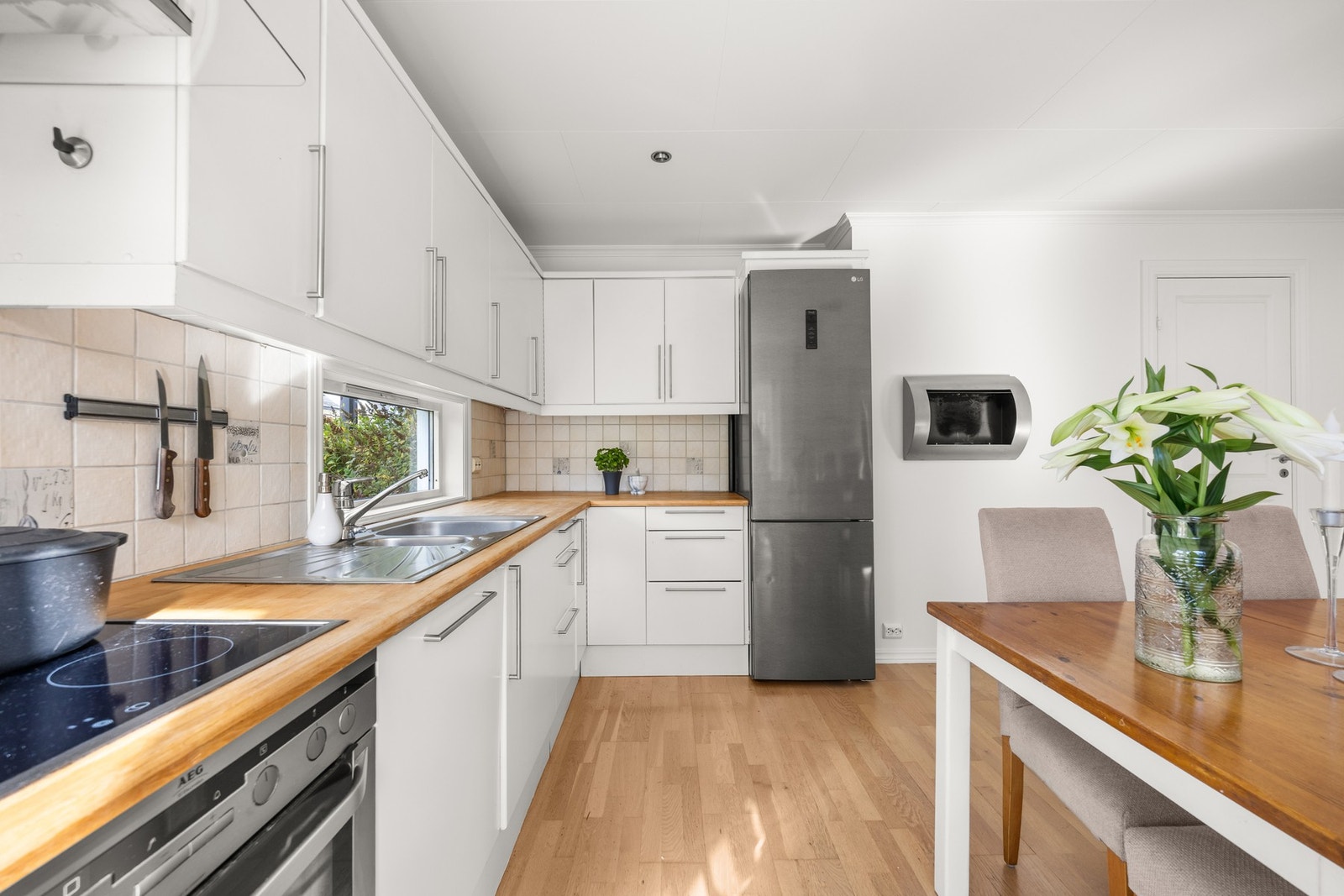 Kjøkkeninnredning med slette fronter, benkeplate av tre og nedfelt oppvaskkum i rustfritt stål med ett-greps armatur Galleribilde