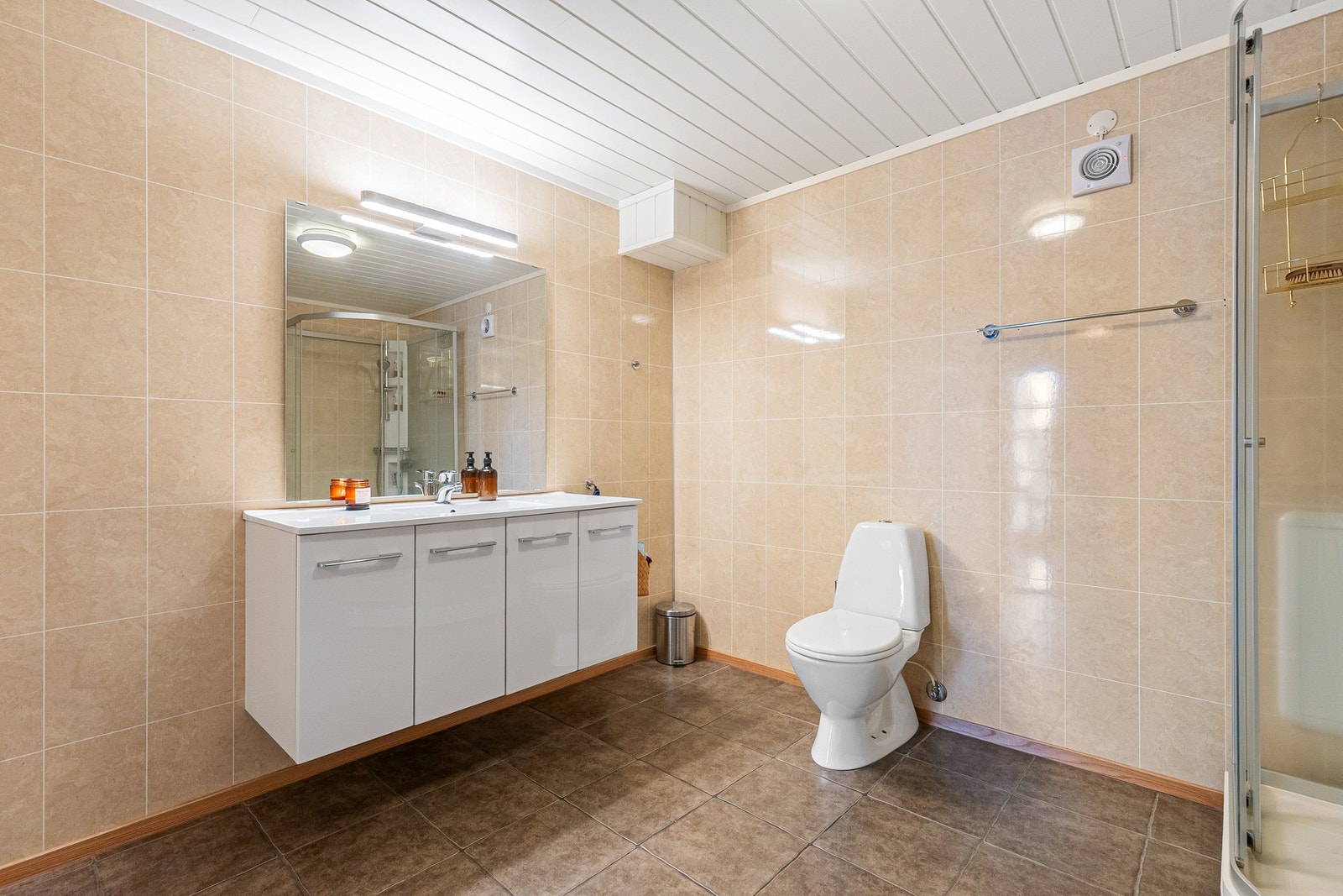 Stort baderom bestående av servant med underskap, dusjkabinett og toalett Galleribilde