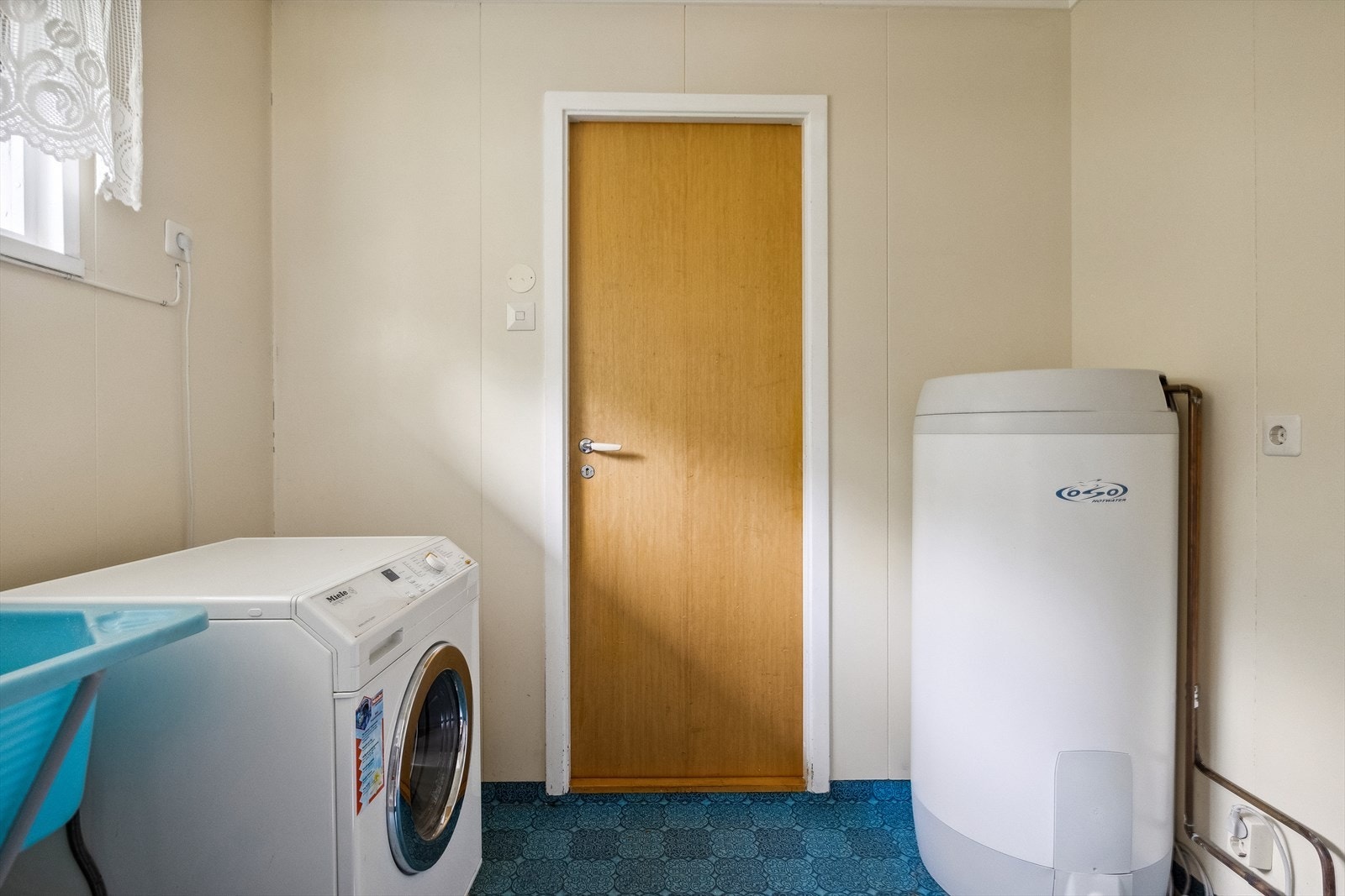- Vaskerom med skyllekar av plast, varmtvannsbereder, opplegg for vaskemaskin og hylleinnredning. Galleribilde