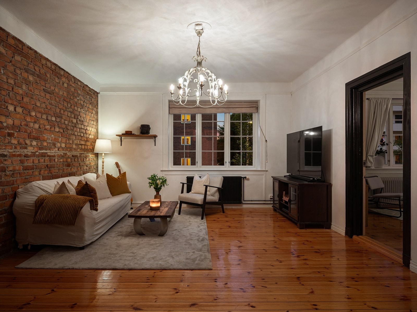 Stuen fremstår sjarmerende med vegg av behandlet teglstein og lakkert tregulv. Galleribilde