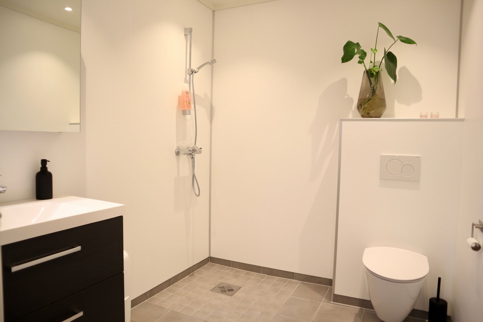 Lyst og lekkert bad i 1.etasje med fliser på gulv og baderomsplater på veggene. Galleribilde