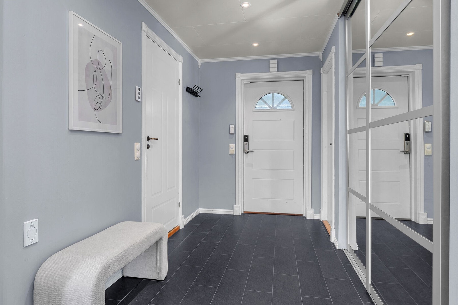 Gang med flislagt gulv og spotbelysning i tak. Galleribilde