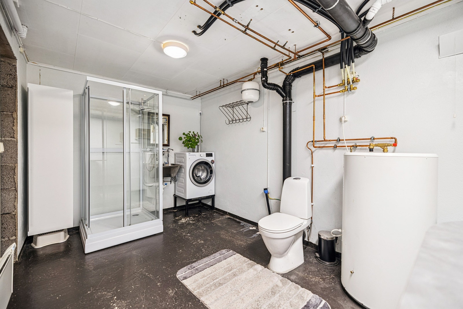 Kombinert bad og vaskerom i kjeller med dusjkabinett og opplegg for vaskemaskin Galleribilde