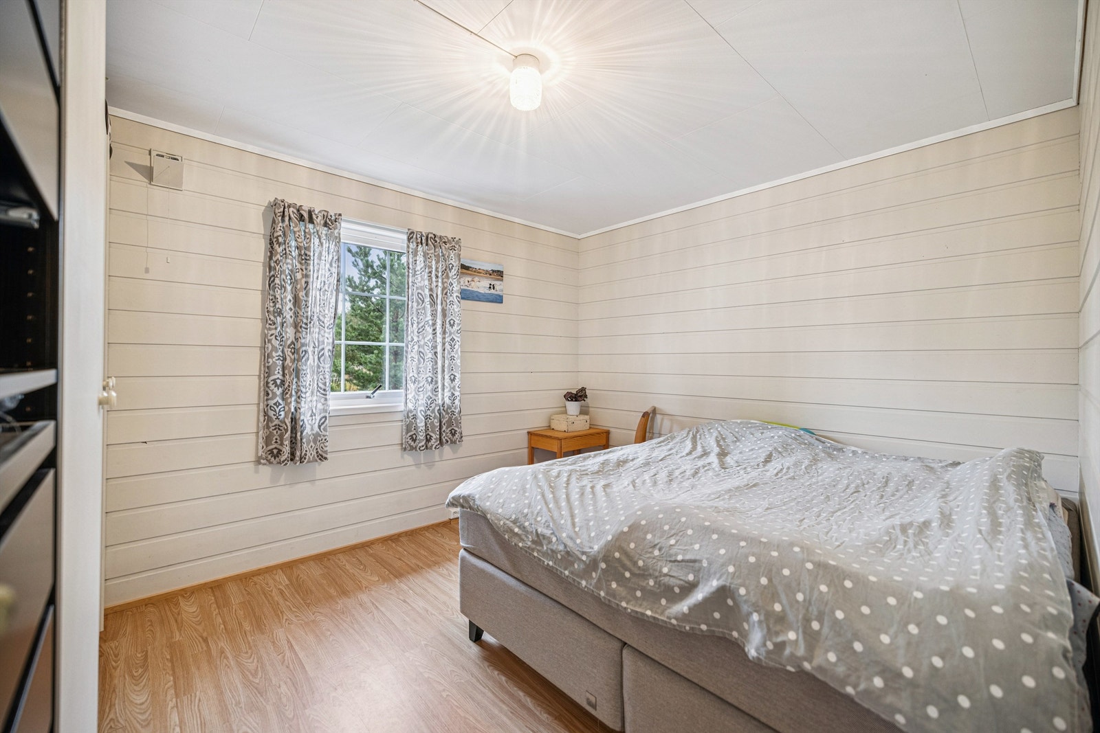 Lyst og trivelig soverom med malt trepanel på veggene Galleribilde