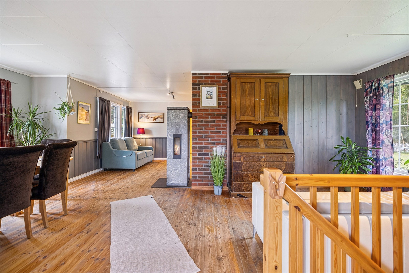 Åpen stue- og spisestueløsning med en sentralt plassert klebersteinsovn Galleribilde