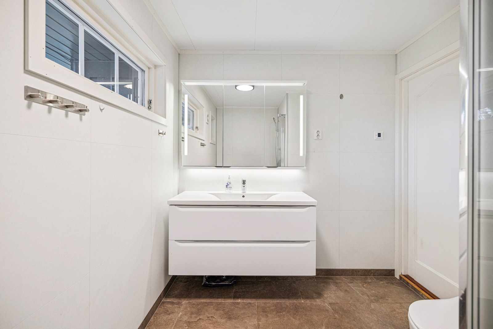 Moderne baderomsinnredning med servantseksjon og speilskap med integrert belysning Galleribilde