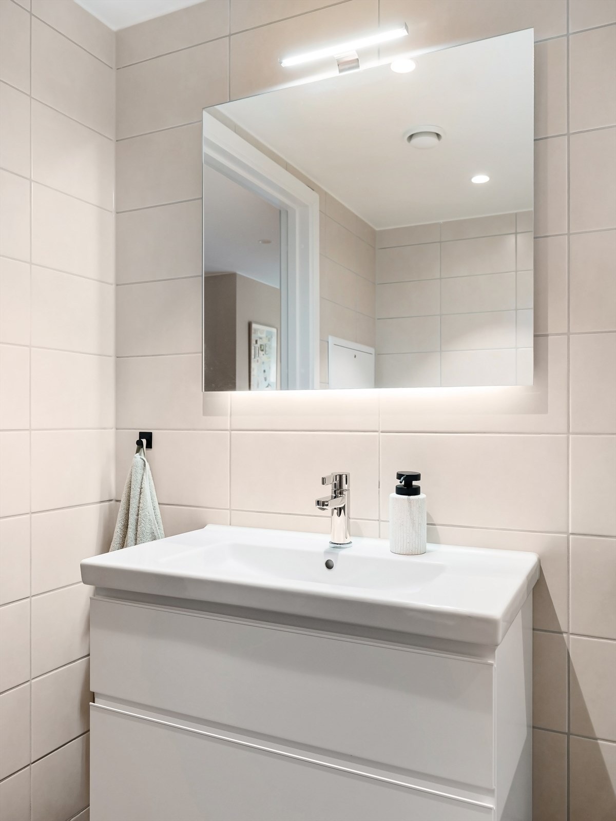 Speil på vegg med overlys over servant. Stikkontakter i skuff under servant Galleribilde