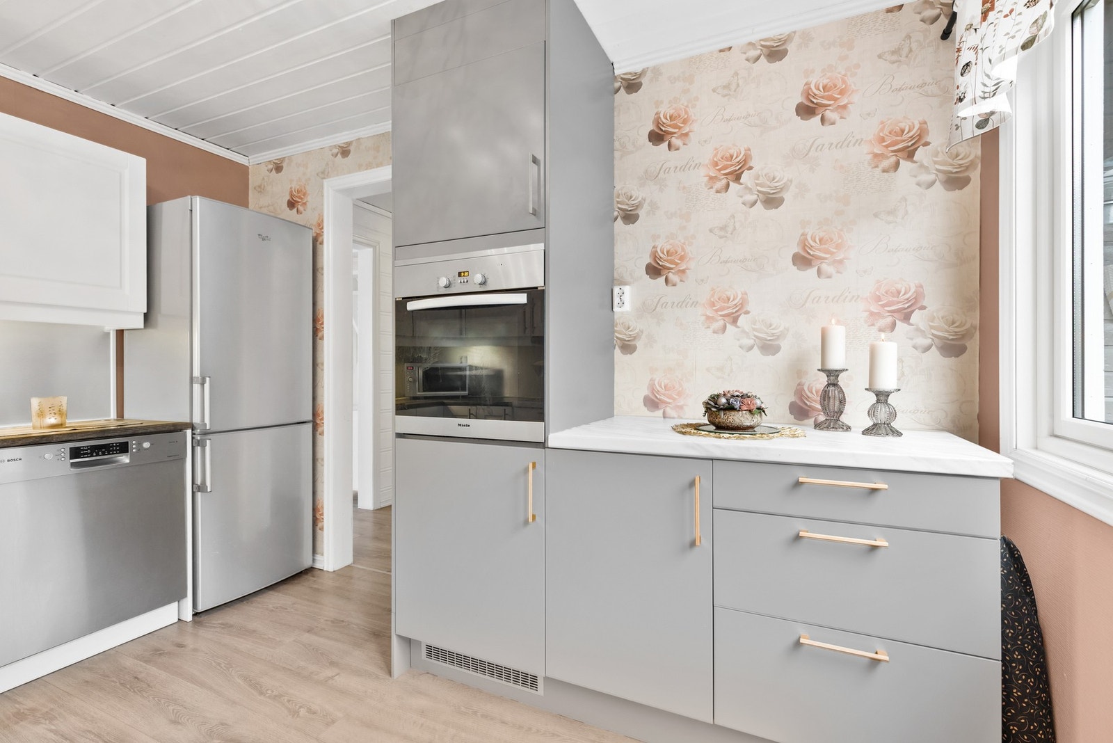 Gulvet er belagt med laminat, vegger med malt strie og beskyttelsesplate over benkeplaten Galleribilde