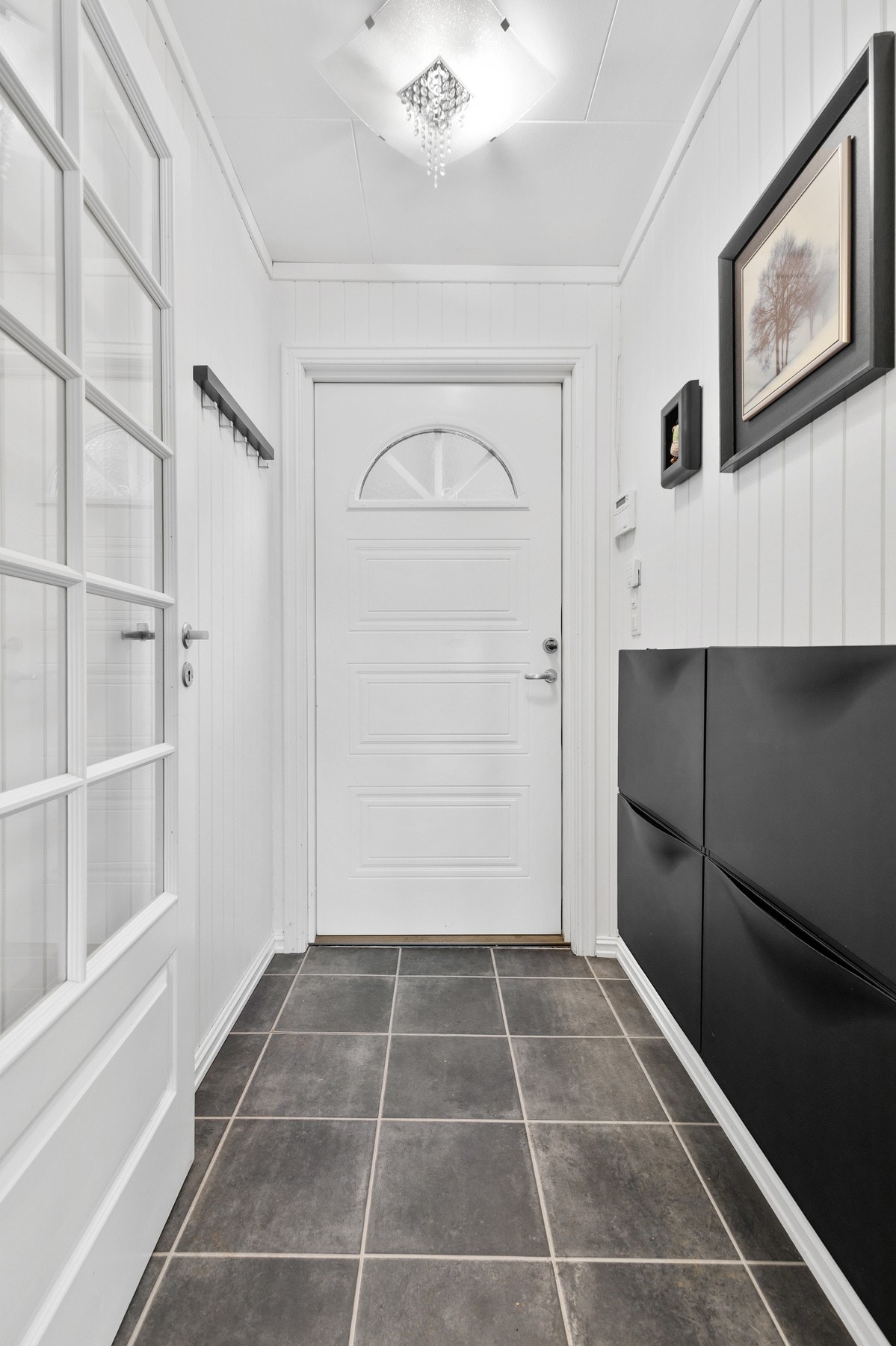 Entréen har flislagt gulv, stående panel på vegger og himling med takplater Galleribilde