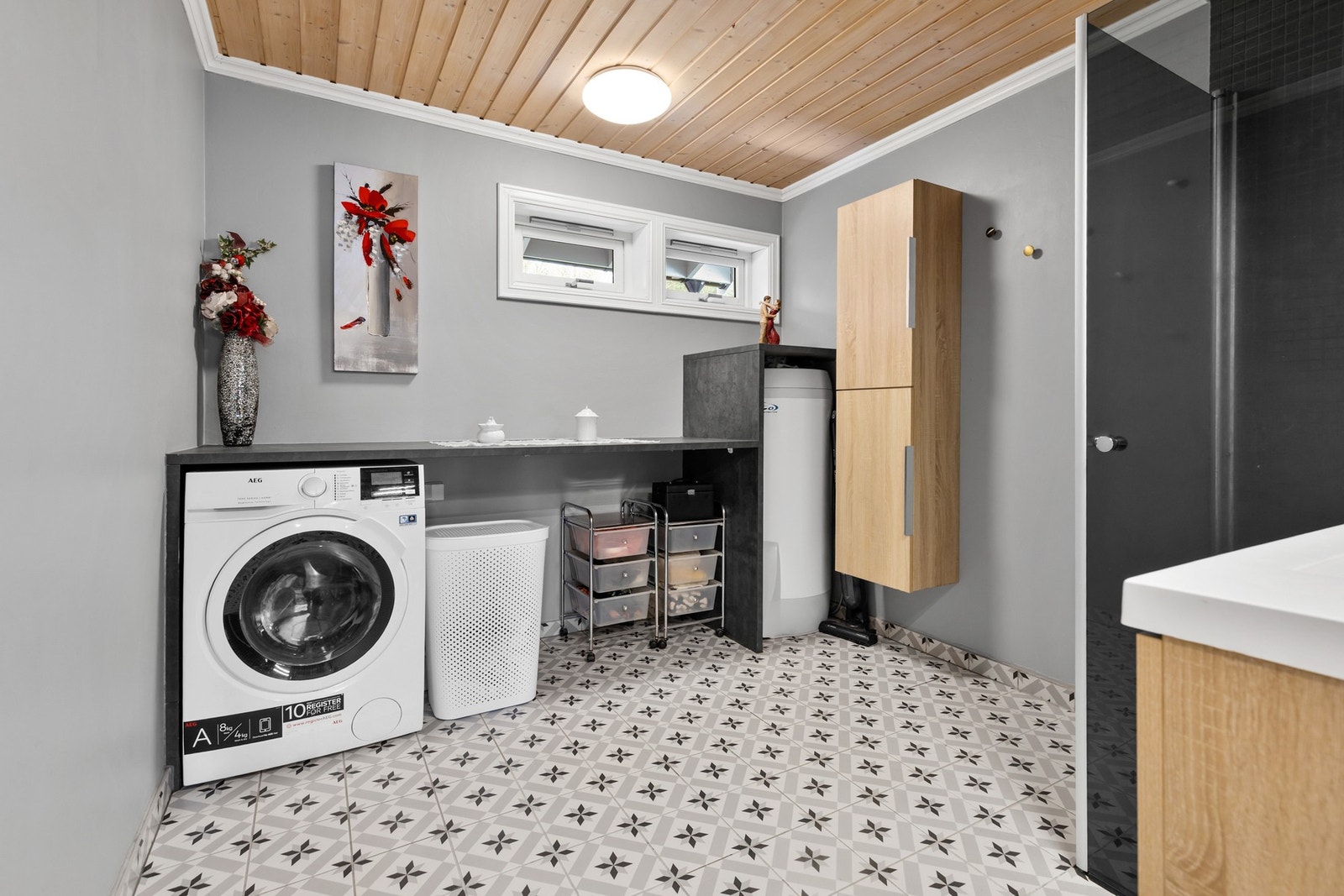 Badet har vegger med fliser og malte plater, samt panel i himlingen. Gulvet er flislagt og utstyrt med elektriske varmekabler Galleribilde