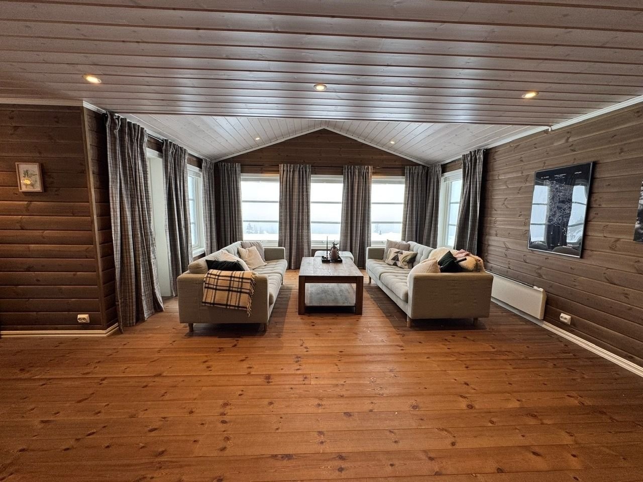 Åpen stue og kjøkkenløsning med store vinduer, masse lys og utsikt utover uten innsyn. Stuen har forhøyet himling. Galleribilde