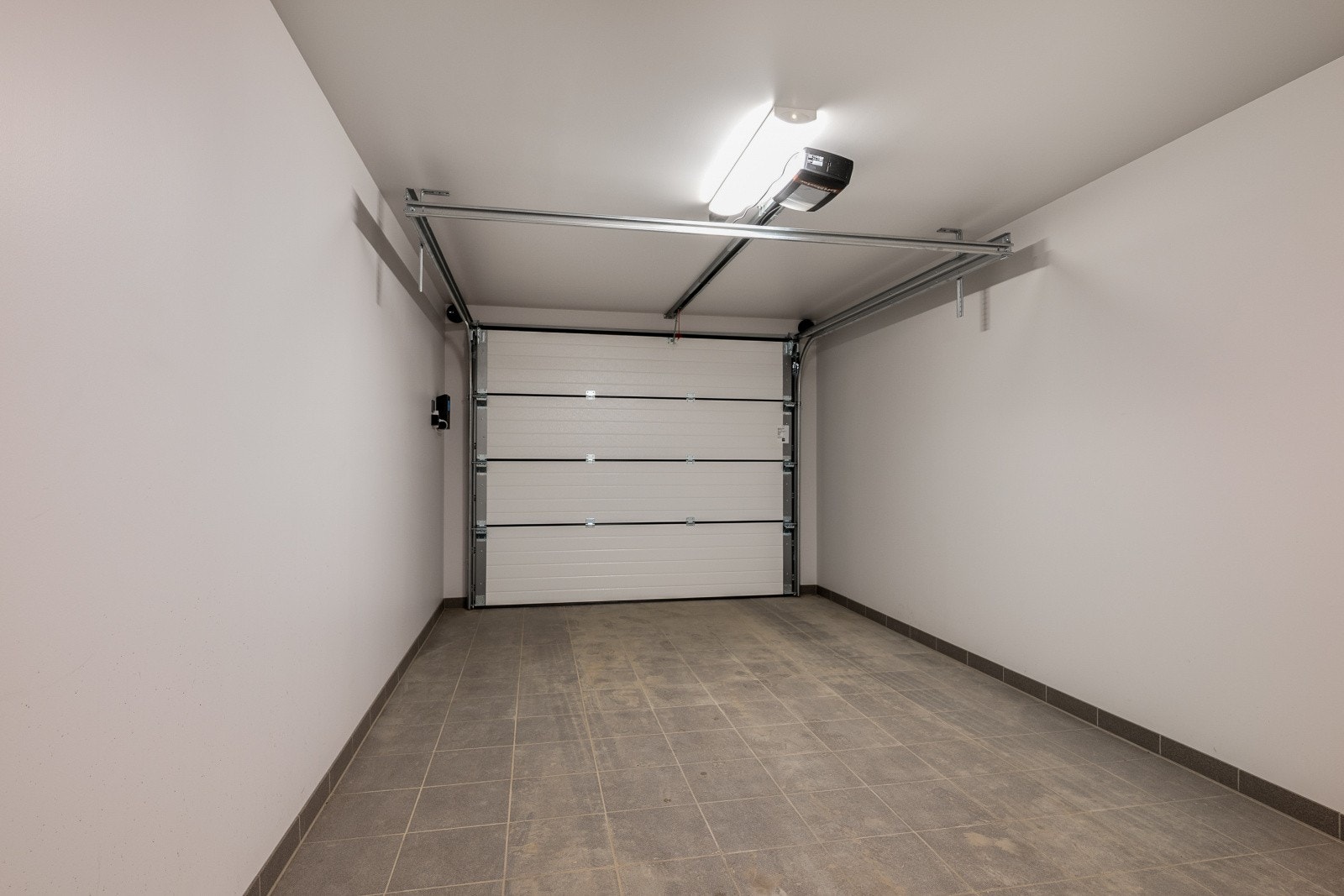 Bilen parkeres i integrert garasje med direkte tilkomst til huset. Her er montert elbillader og skistativ. Galleribilde