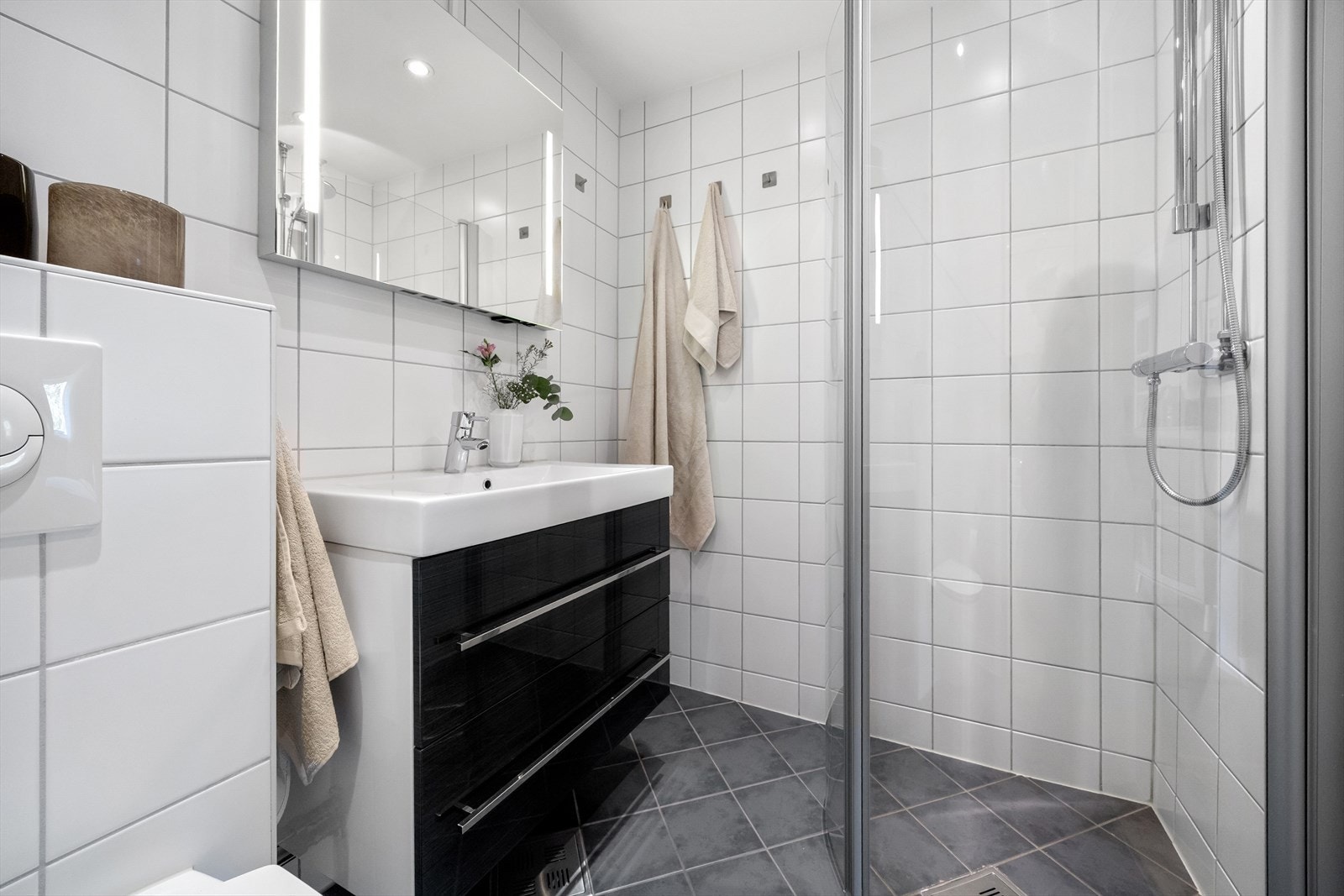 Badet har varmekabler i gulv, praktisk dusjhjørne med innfellbare dusjdører og servant med innredning. Galleribilde