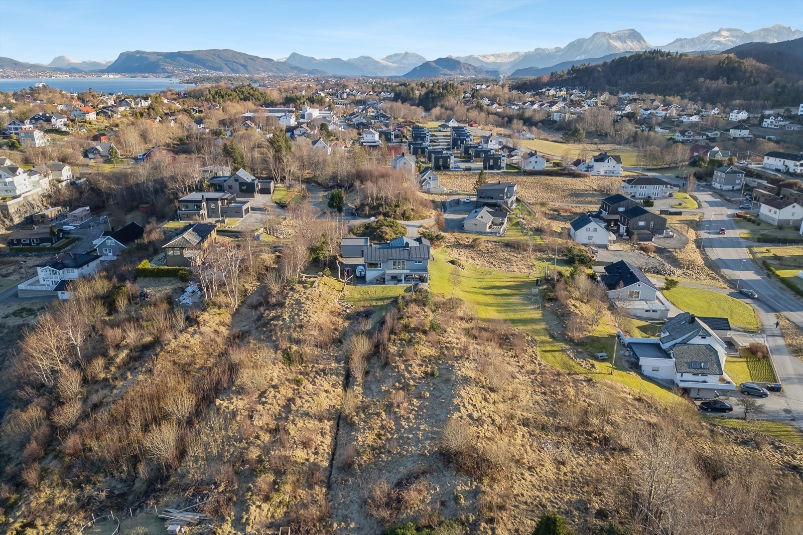 Dronebilde av tomten og de øvrige eiendommene som er til salgs. Tomten er delvis veiareal samt boligareal Galleribilde