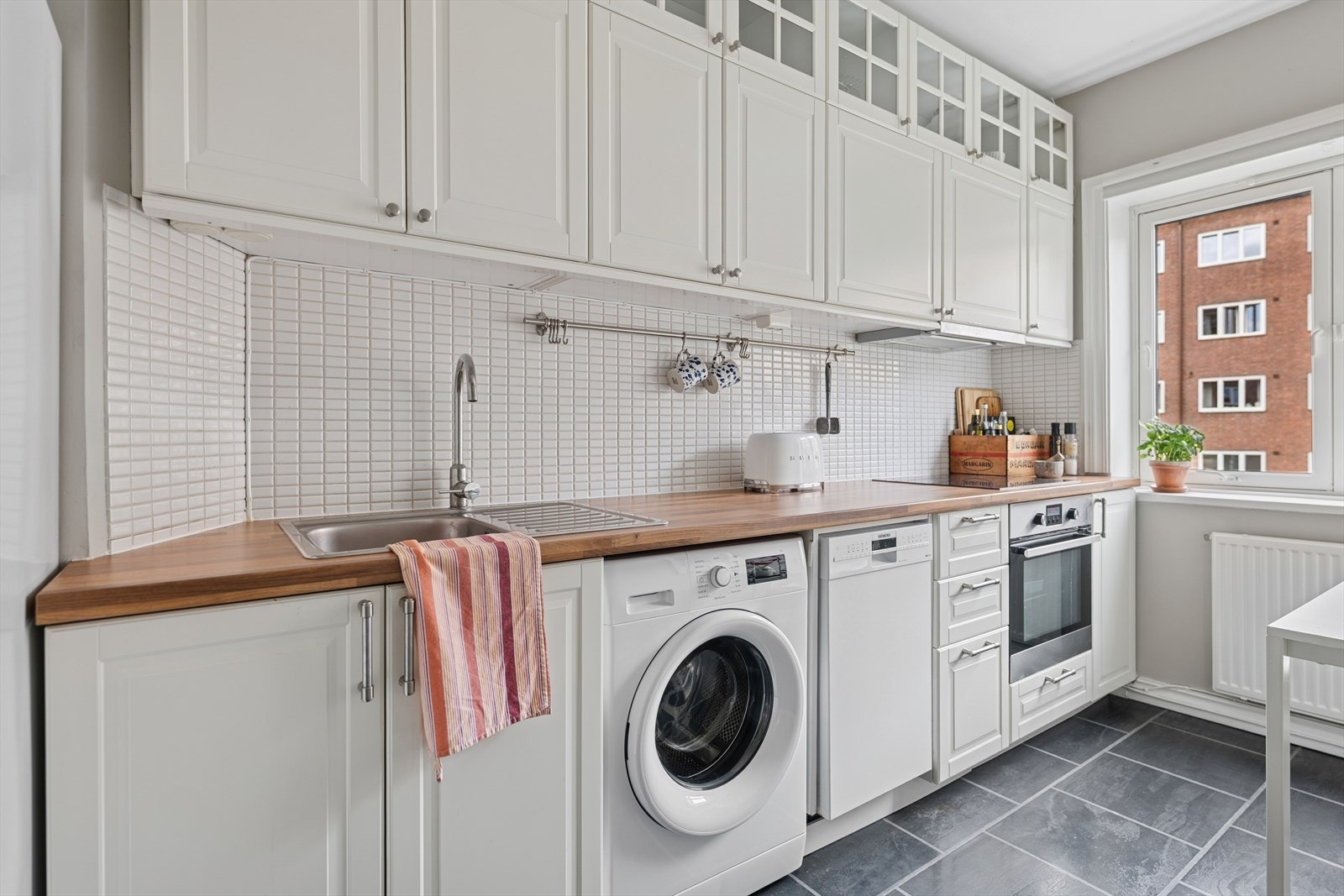 Kjøkkenet er med lyse flater og høye overskap byr på rikelig med plass for oppbevaring! Galleribilde