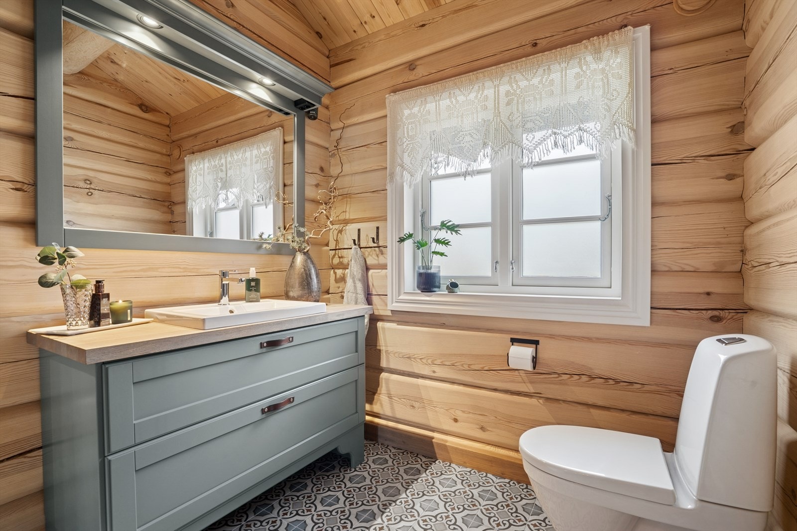 Hovedbadet har fliser på gulv med varme, tømmer på vegger og panel i tak. Galleribilde