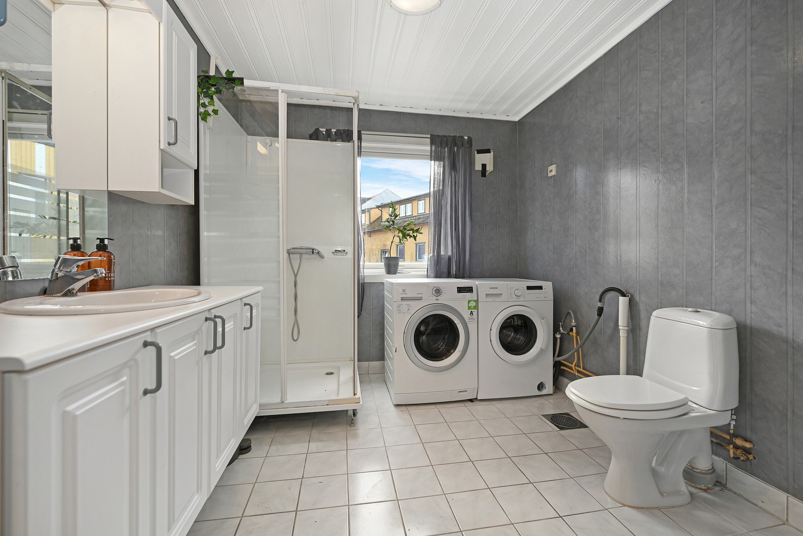 Bad med flislagt gulv og våtromstapet på veggene. Galleribilde