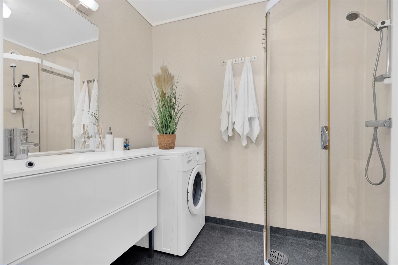 Pent bad som er innredet med moderne baderoms-innredning, toalett og dusjnisje. Opplegg for vaskemaskin. Galleribilde