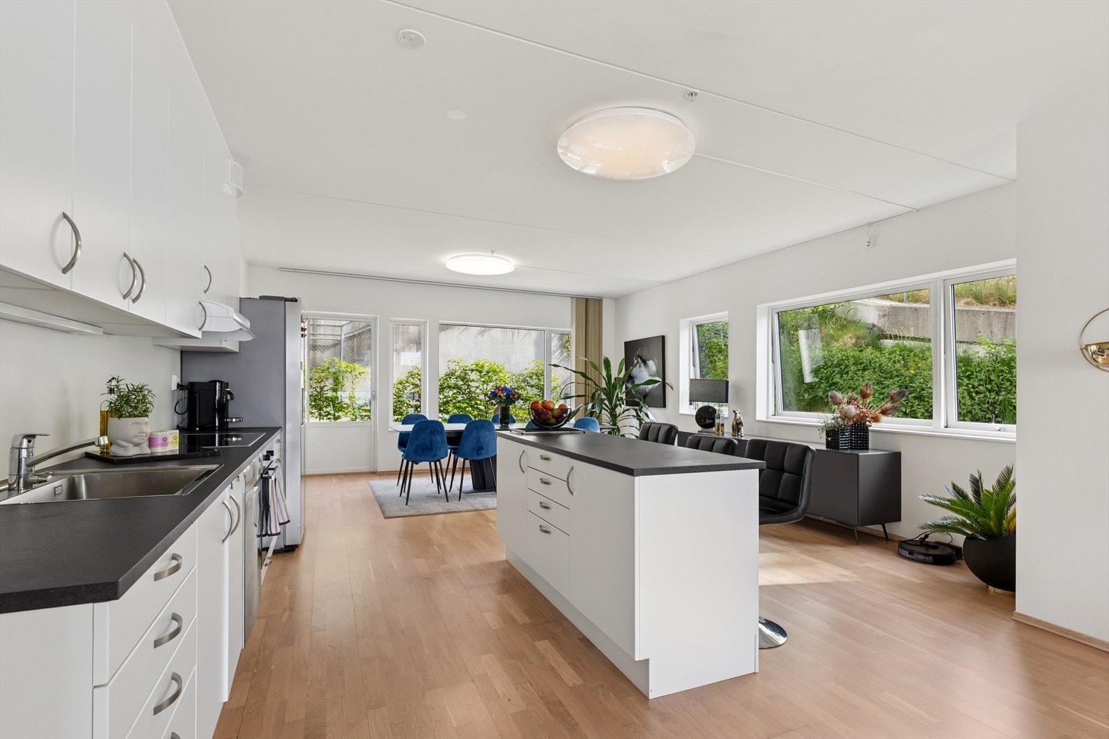 Kjøkkenet har en stilren innredning med hvite, glatte fronter og en praktisk benkeplate i laminat. Galleribilde