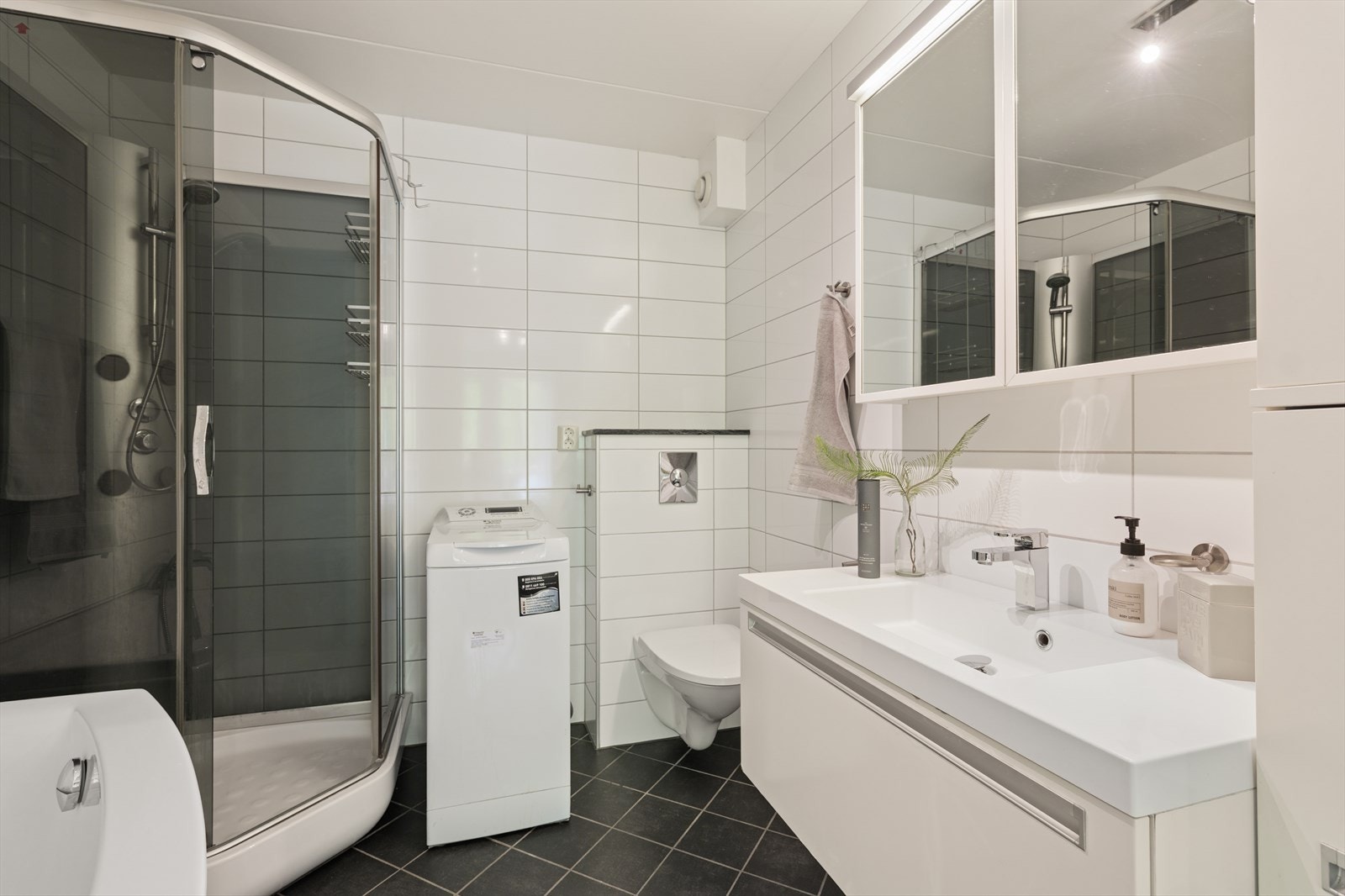 Badet er pusset opp i 2010 og er tidløst innredet med grå fliser på gulvet og hvite fliser på vegg. I gulvet har man også varmekabler for ekstra komfort. Galleribilde