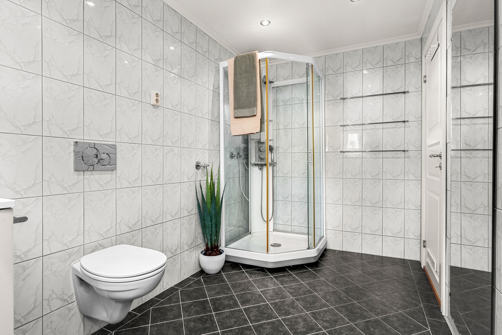 Badet måler 6,9 kvm og er utstyrt med gulvvarme, dusjkabinett og downlights i taket Galleribilde