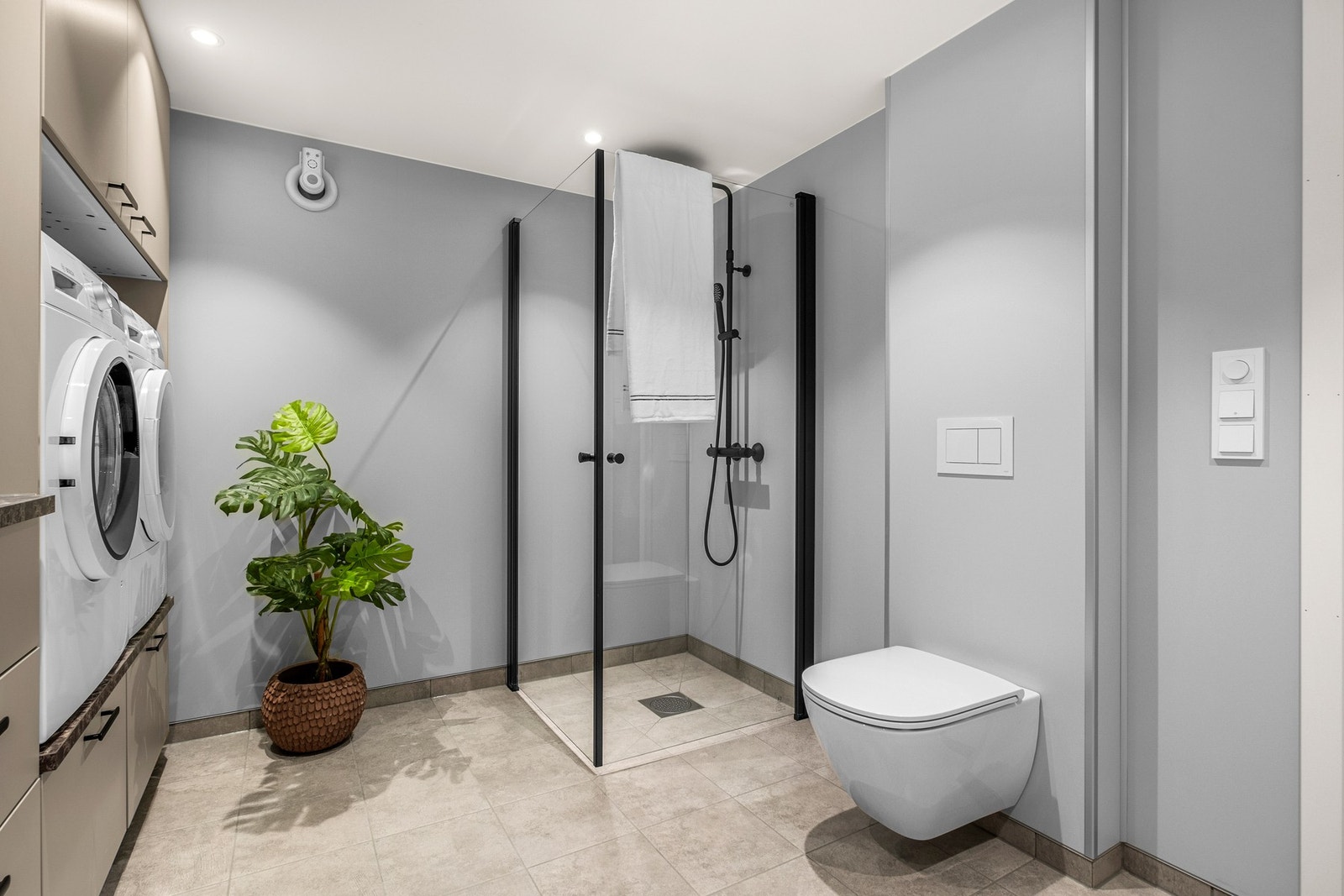 Badet er utstyrt med gulvvarme, dusjhjørnet med innfellbare glassvegger, opplegg for vaskemaskin og veggmontert speil med integrert belysning Galleribilde