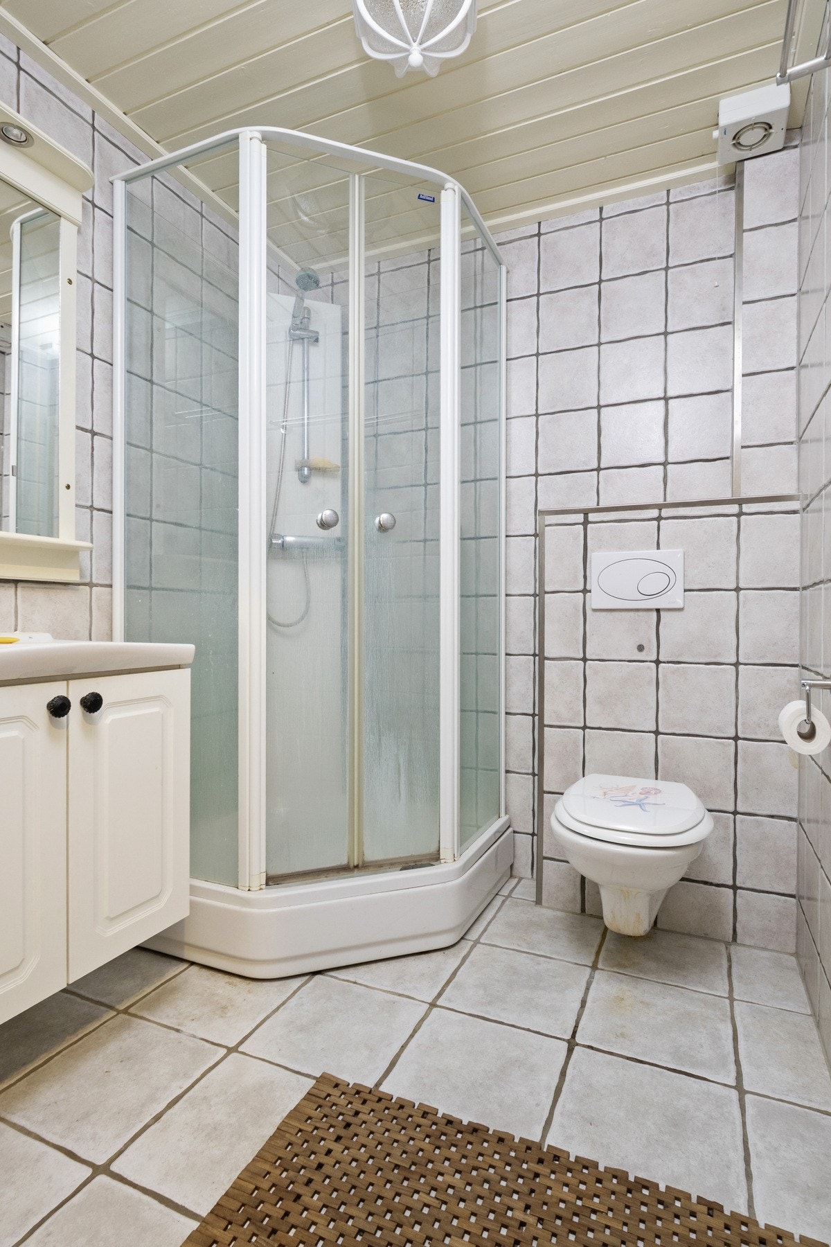 Det andre badet har et moderne uttrykk med grå fliser på både vegger og gulv. Også her er det varme i gulvet, samt dusjkabinett, vegghengt toalett og servantskap med speil og belysning. Galleribilde