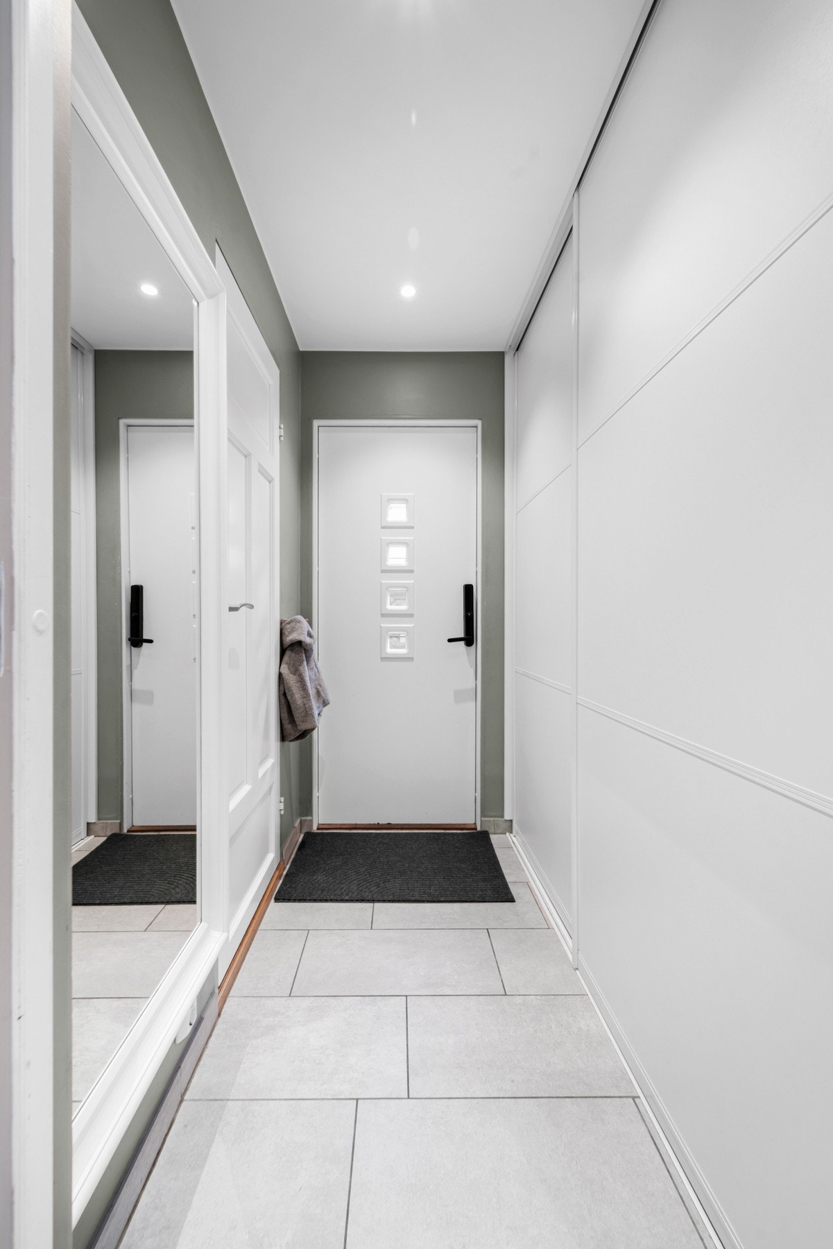Flislagt entré med gulvvarme og stor skyvedørsgarderobe | Inngang til vaskerom fra entréen Galleribilde
