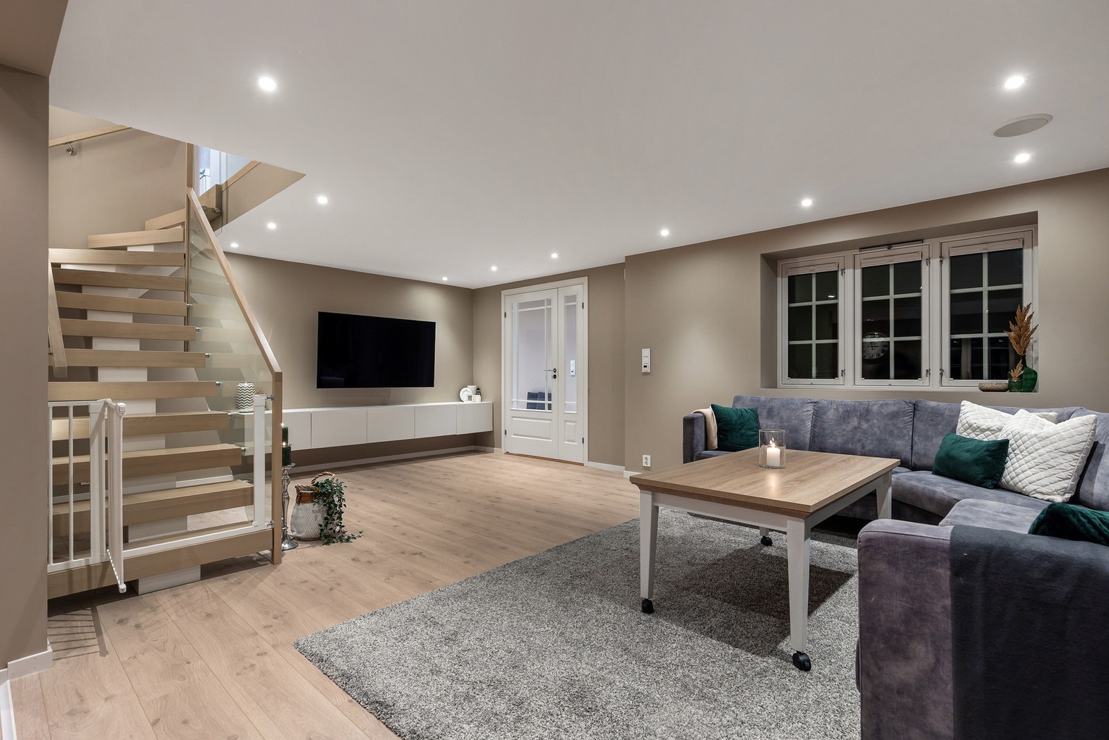 Tiltalende stue med 1-stavs laminatgulv og varmefolie, slette flater på vegger og himling med utstrakt bruk av downlights i tillegg til høytallere i himling. Lyd og lys kan fjernstyres via app på telefon. Galleribilde