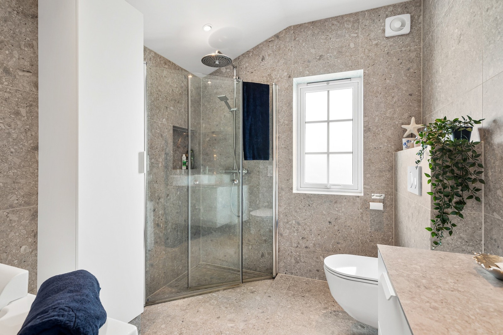 Rommet har innredning med nedfelt servant, veggmontert toalett og dusjhjørne Galleribilde