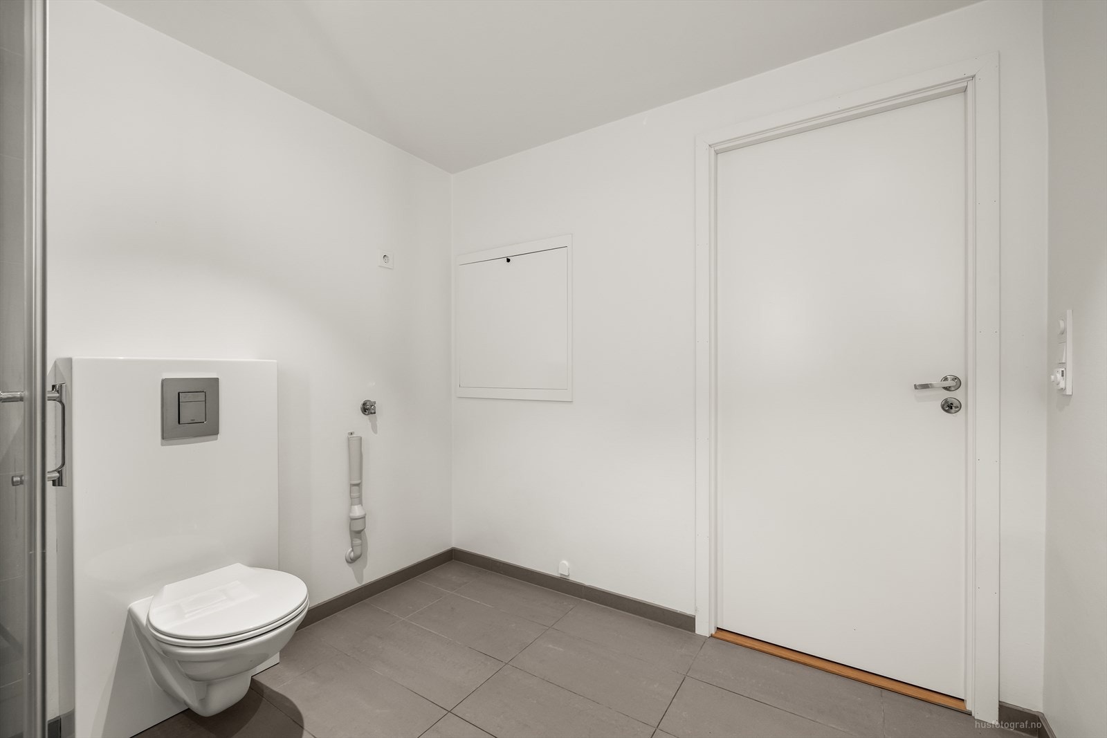 Moderne baderomsinnredning med nedfelt servant, veggmontert toalett og dusjvegger/hjørne. Rommet har opplegg for vaskemaskin. Galleribilde