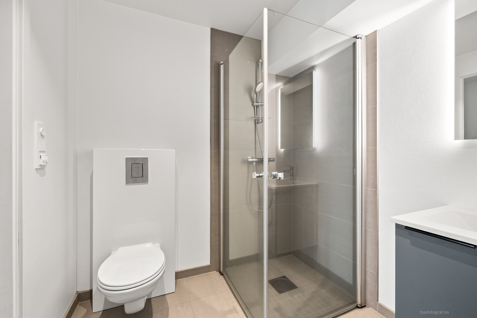 Delikat innredet bad med fliser på gulv i en beige fargetone og mosaikkfliser i dusj sonen. Galleribilde