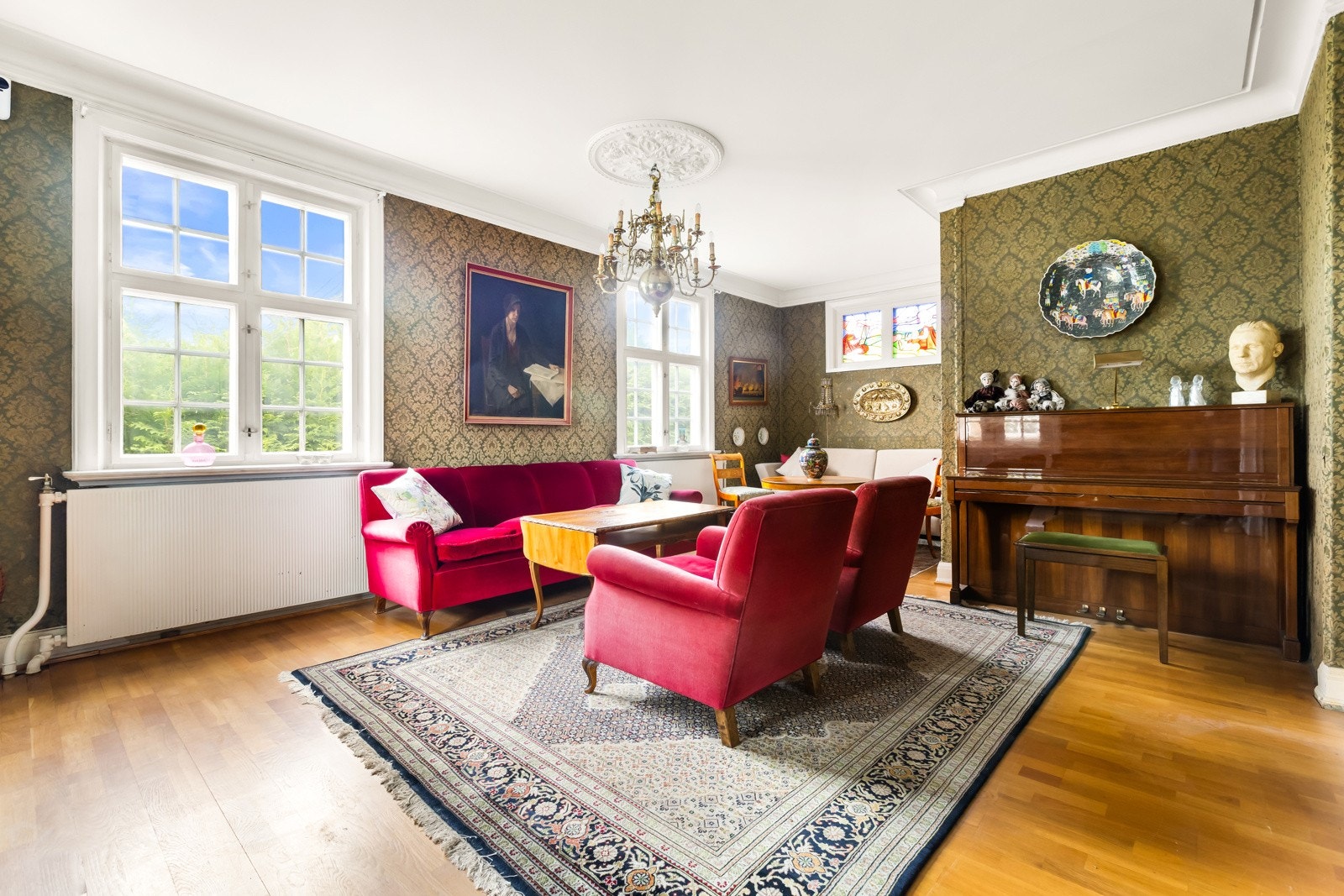 Stor stue med særpreget tapet, kunstferdige blyglassvinduer mot nord og store vinduer mot vest. Galleribilde