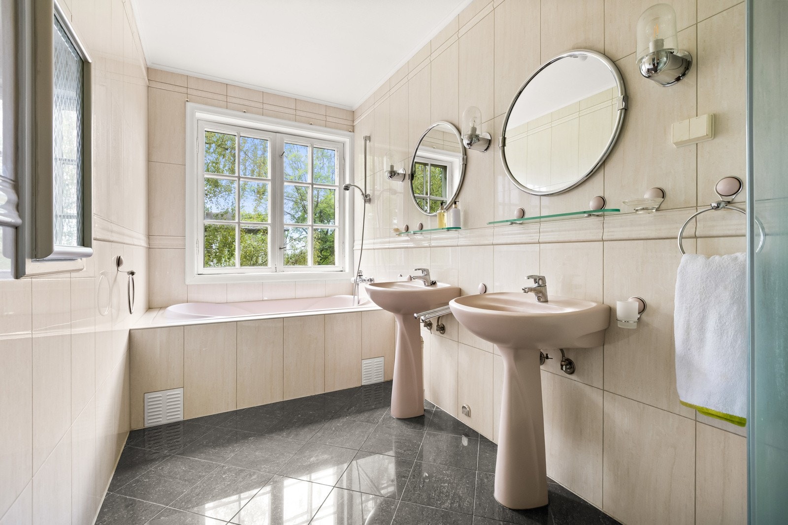 Bad 1 (master). Flislagt bad med varmekabler (disse er ikke funksjonstestet). Rommet er utstyrt med innfliset badekar, dusjkabinett, samt to gulvstående servanter. Over servantene er det montert to vegghengte speil og belysning. Naturlig ventilasjon. Galleribilde