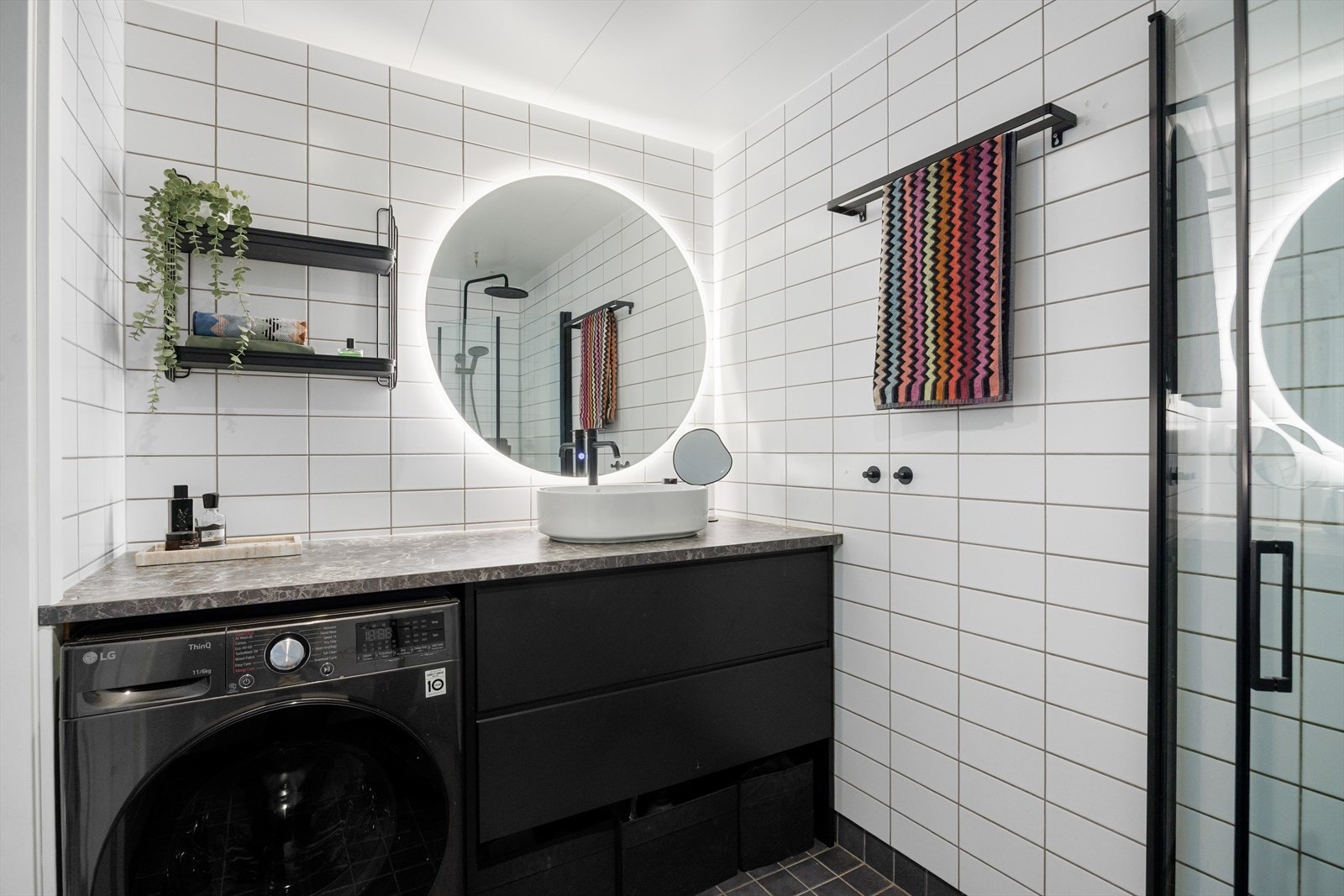 Rommet er innredet med ny innredning fra 2025, inkludert laminat benkeplate med underskap, toppmontert servant og speil med integrert berøringslys. Videre har badet vegghengt toalett med innebygd sisterne samt dusjsone med innfelte dusjdører. Galleribilde