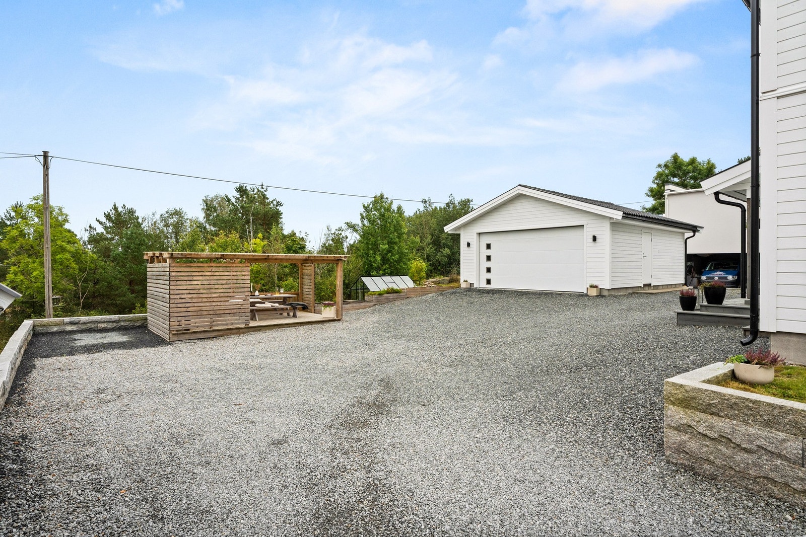 Stor gårdsplass med uteplass og garasje. Galleribilde