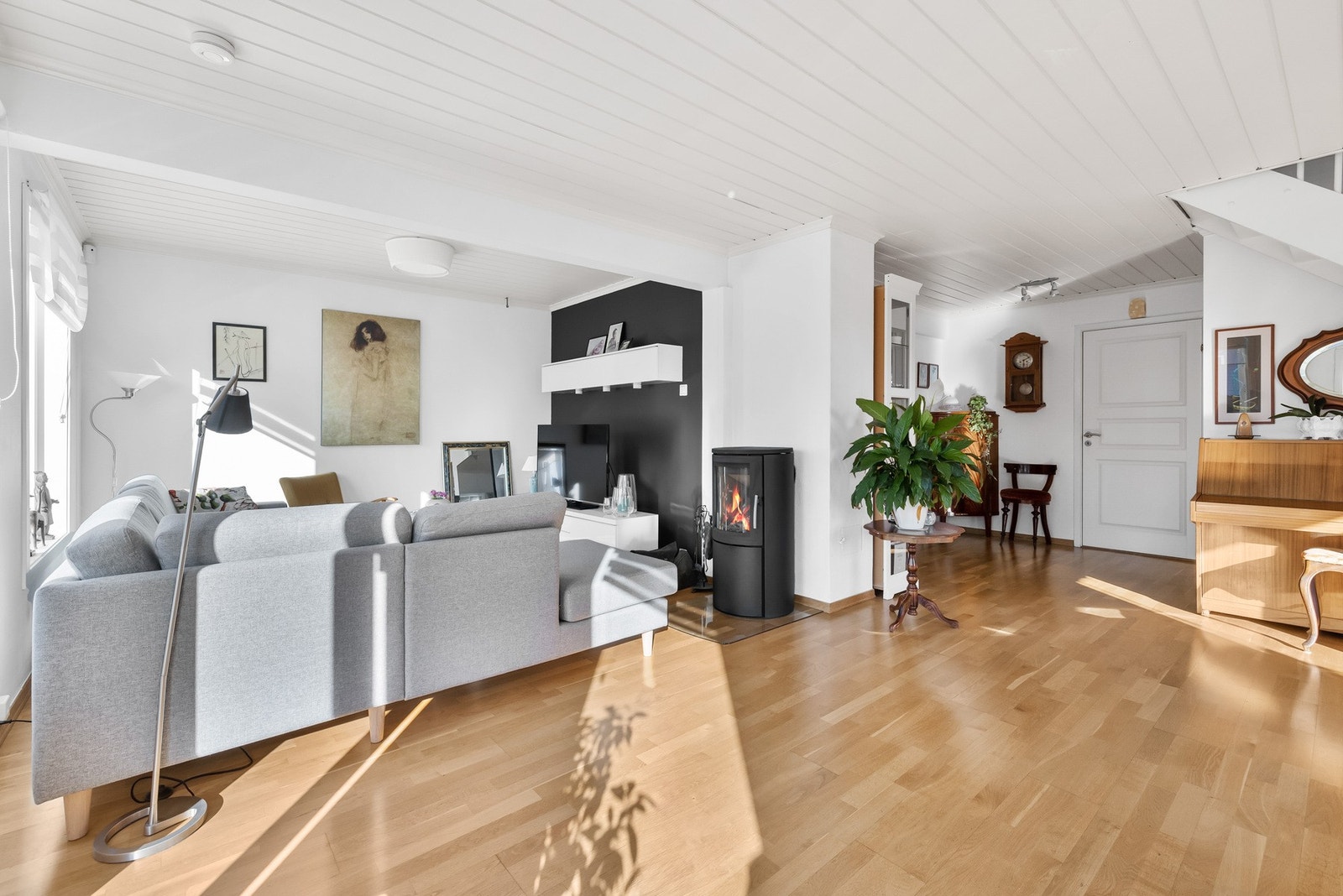 Lyst og romslig stue med store vinduer, peisovn og utgang til balkong. Galleribilde