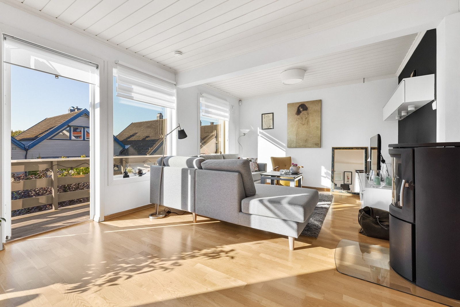 Lyst og romslig stue med store vinduer, peisovn og utgang til balkong. Galleribilde