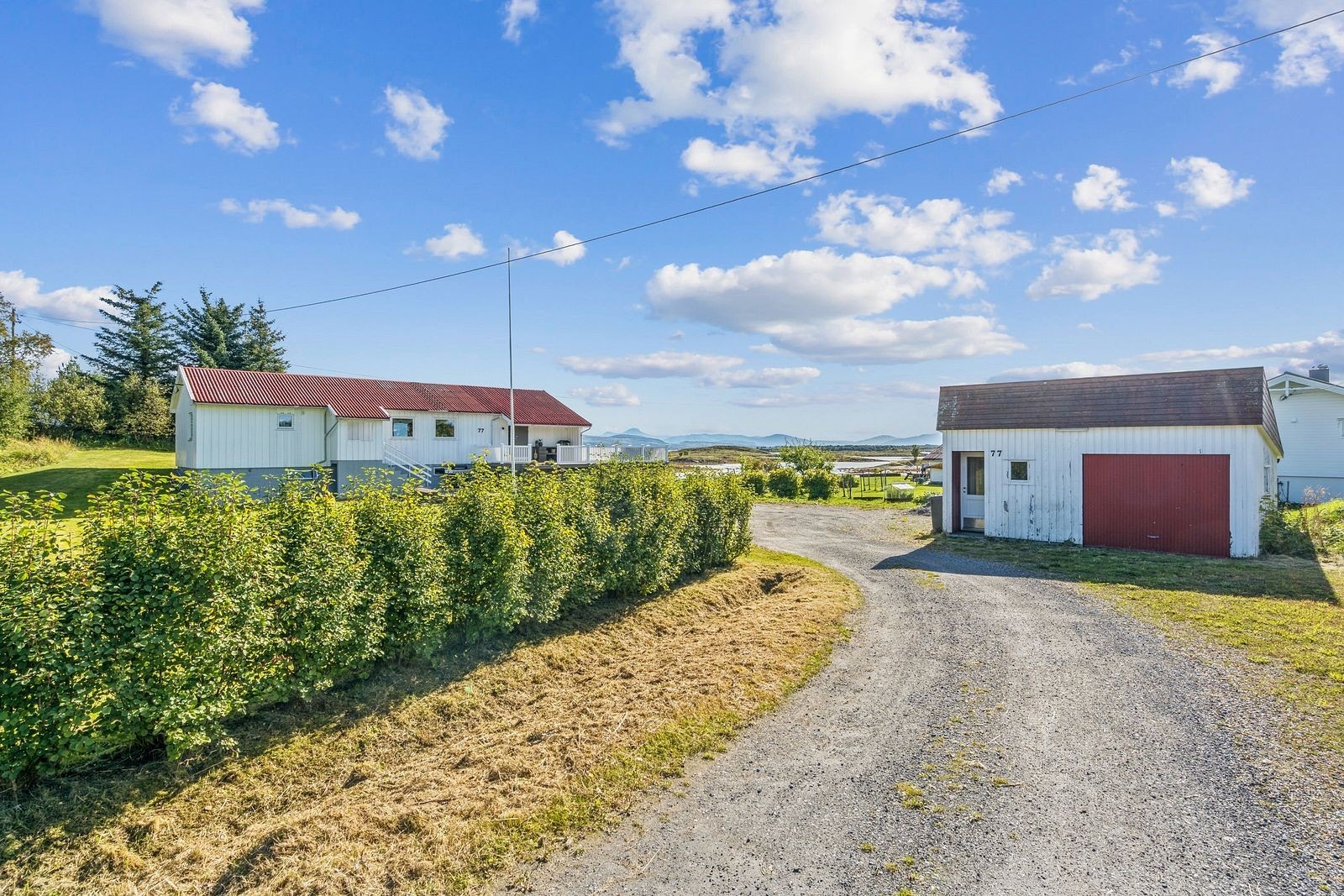 Boligen ligger tilbaketrukket fra hovedveien, mens hagen rammes inn av en hekk som gir lite innsyn til boligens utearealer. Galleribilde