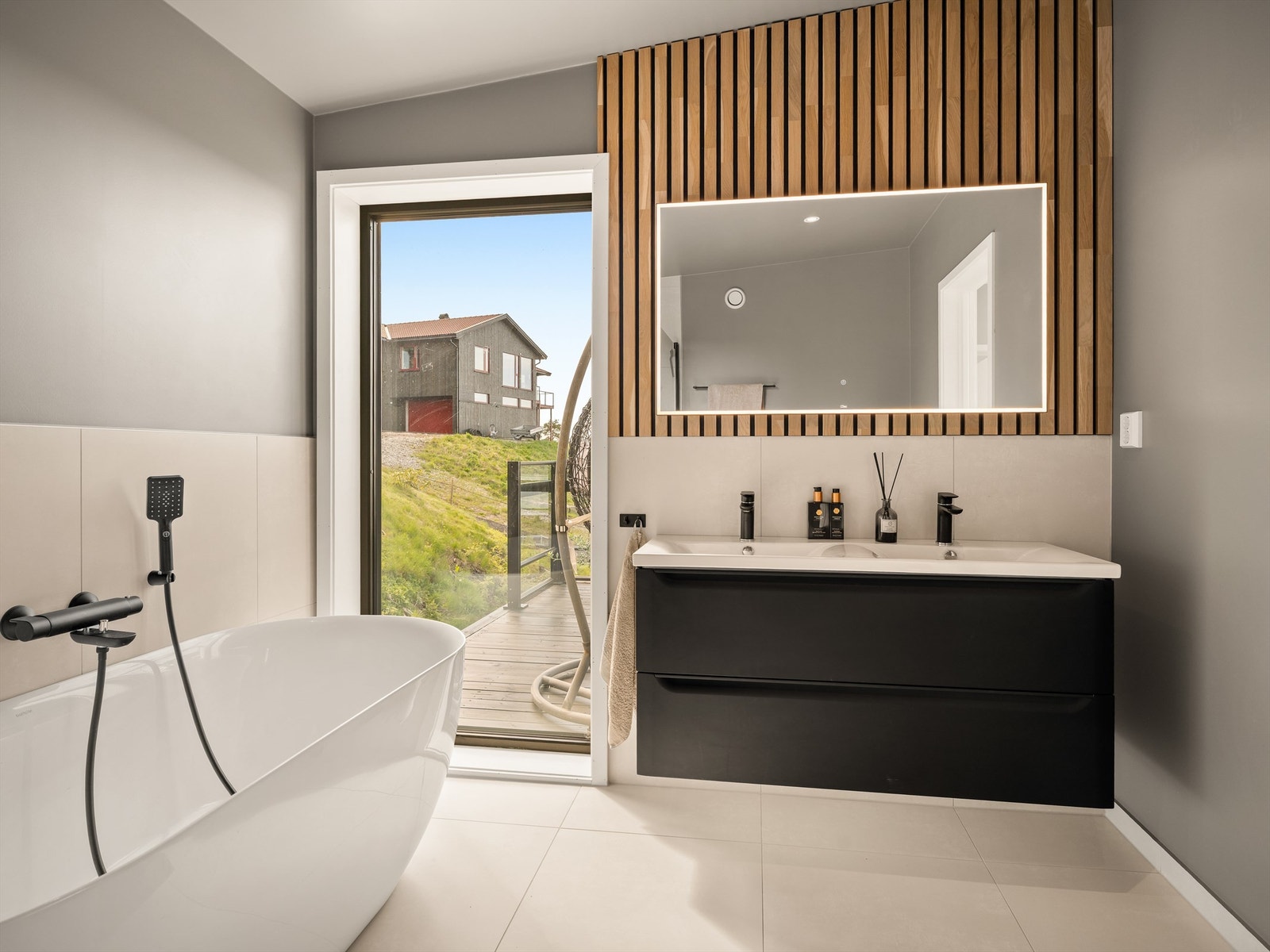 Badets overflater er utført med en vellykket kombinasjon av lyse storformat fliser, akustikkpanel og glatte minimalistiske flater. Galleribilde