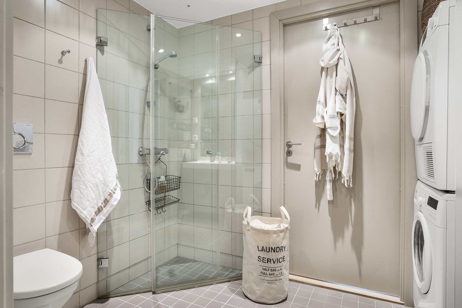 Moderne, flislagt bad med gulvvarme og opplegg for vaskemaskin og tørketrommel. Galleribilde