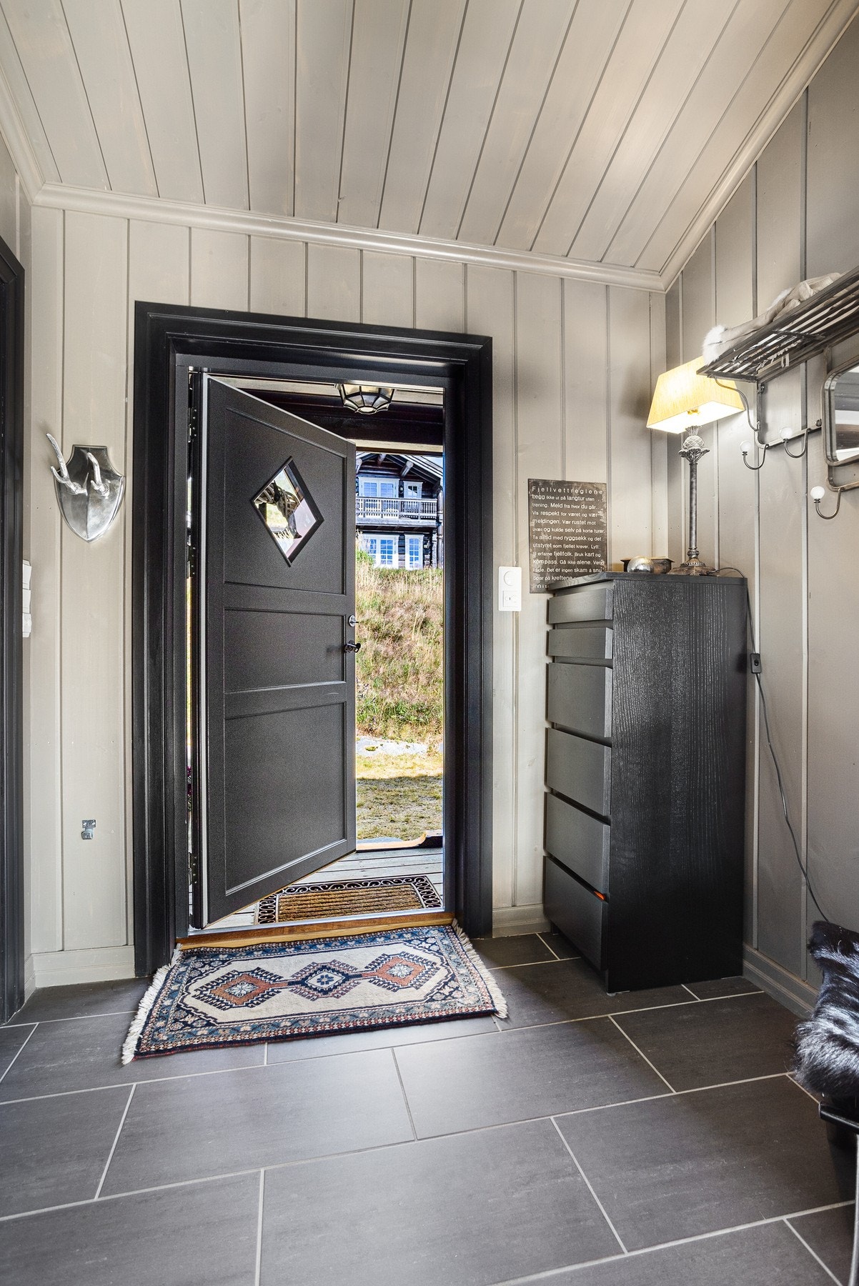 Innbydende entré med flislagt gulv og gulvarme. Hovedentréen holdes enkelt ryddig ettersom eierne av hytta har egen inngang via garasje og skistall Galleribilde