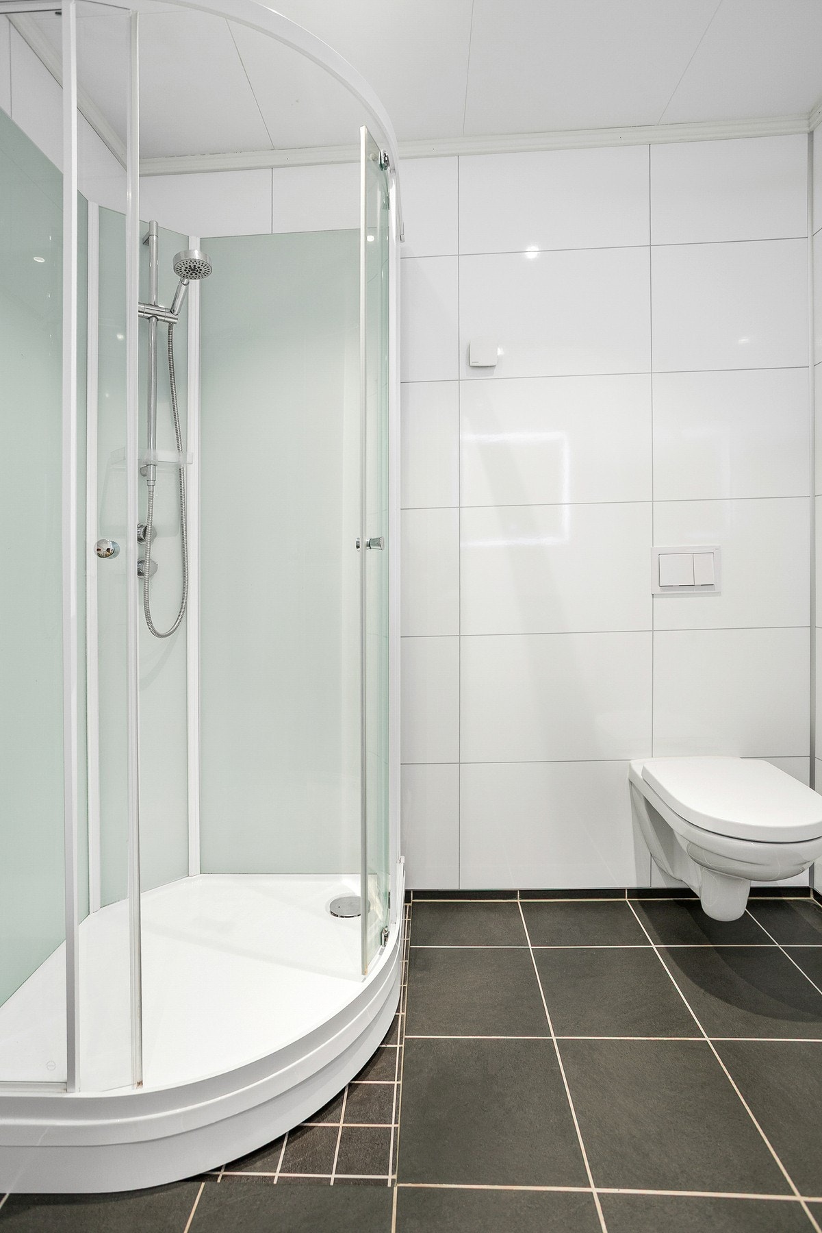 Bad i hybel med vegghengt toalett og dusjkabinett. Galleribilde