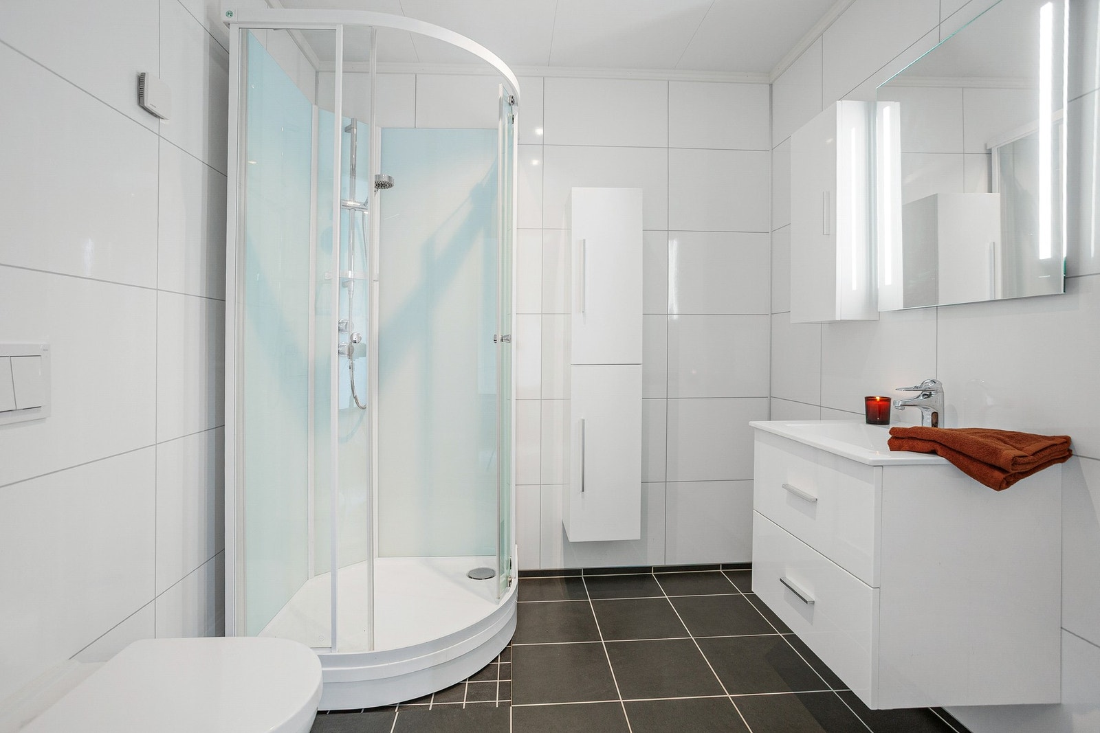 Badet har en romslig innredning med god plass til lagring og flislagt gulv. Galleribilde