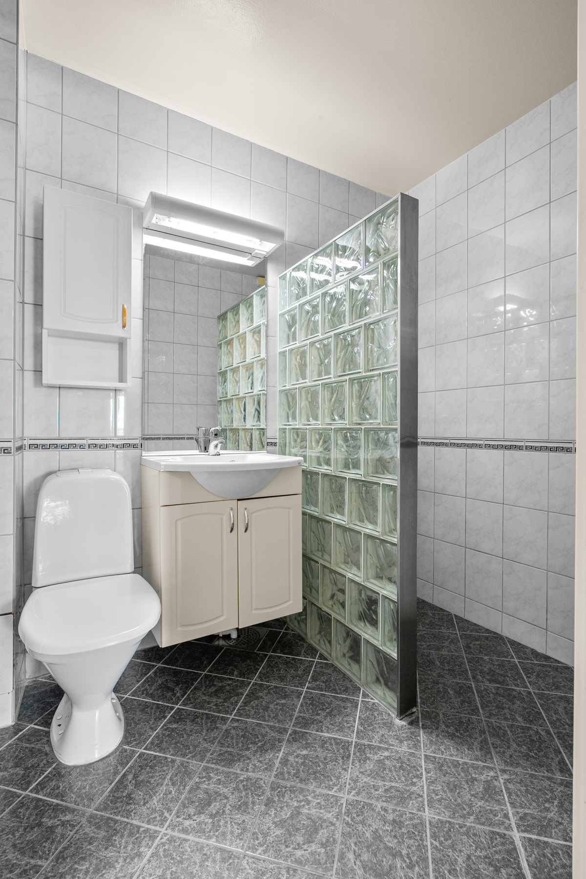 Tidløst bad med flislagte vegger og gulv fra ca. 1998. Borettslaget gjennomførte innvendig rehabilitering av avløpsrør i 2014-2017. Galleribilde