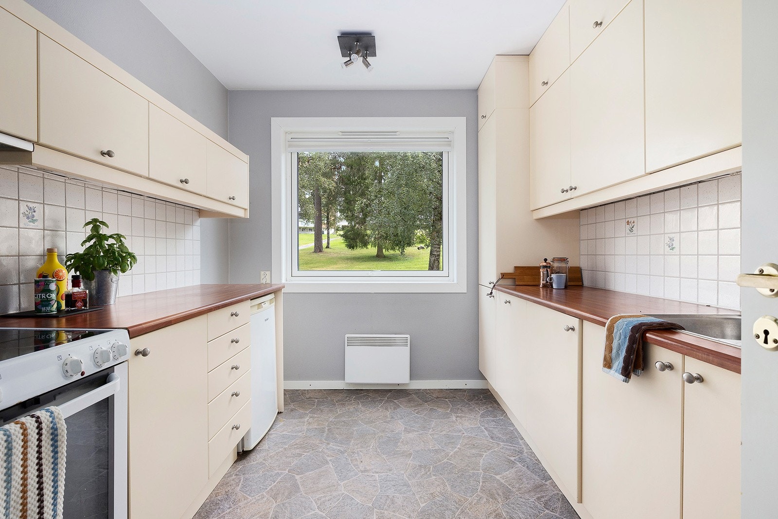 Kjøkken med glatte fronter og laminatbenk, utstyrt med integrert oppvaskmaskin og fliser over benk. Galleribilde