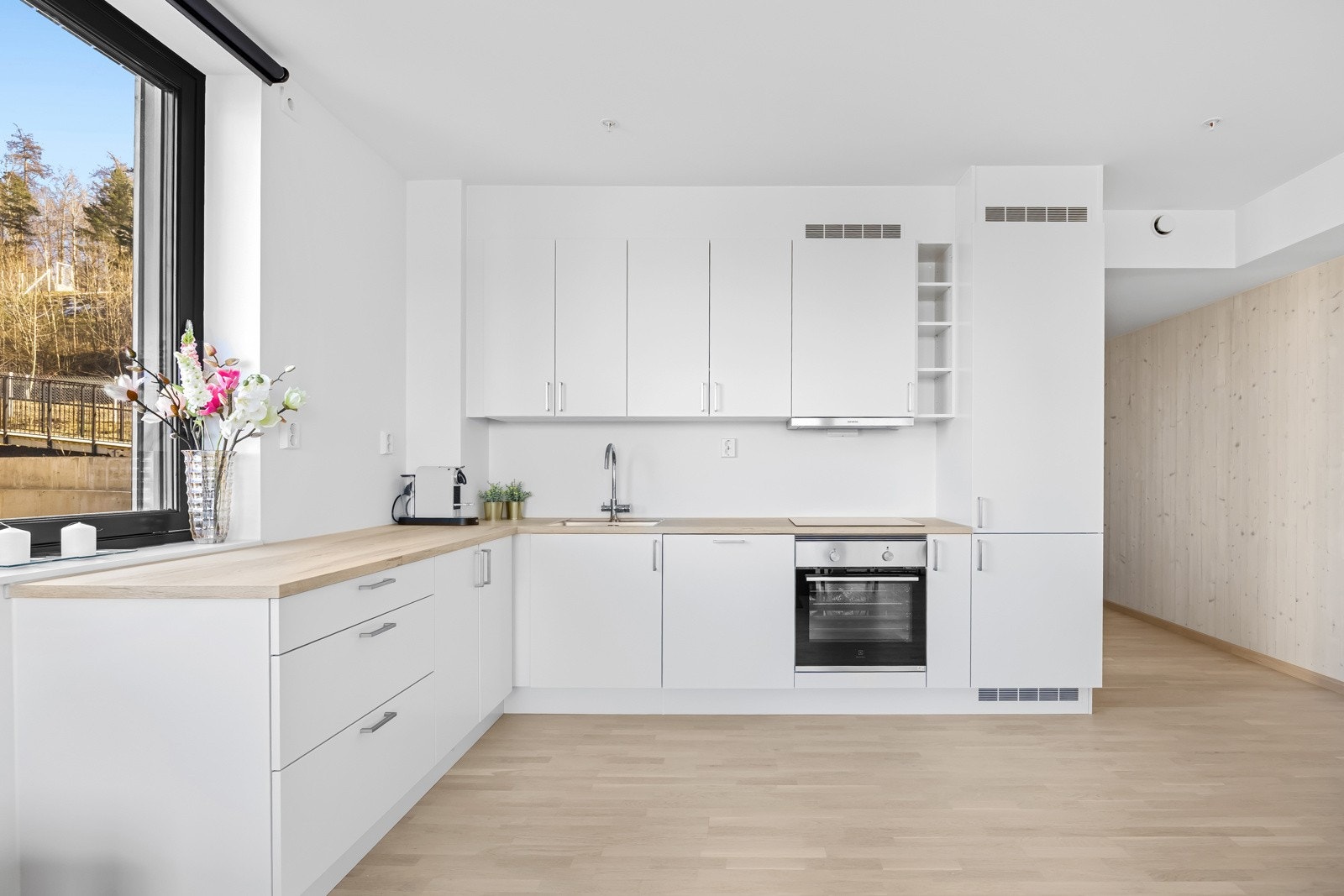 Pent og lyst kjøkken med glatte fronter og en benkeplate i laminat. Galleribilde