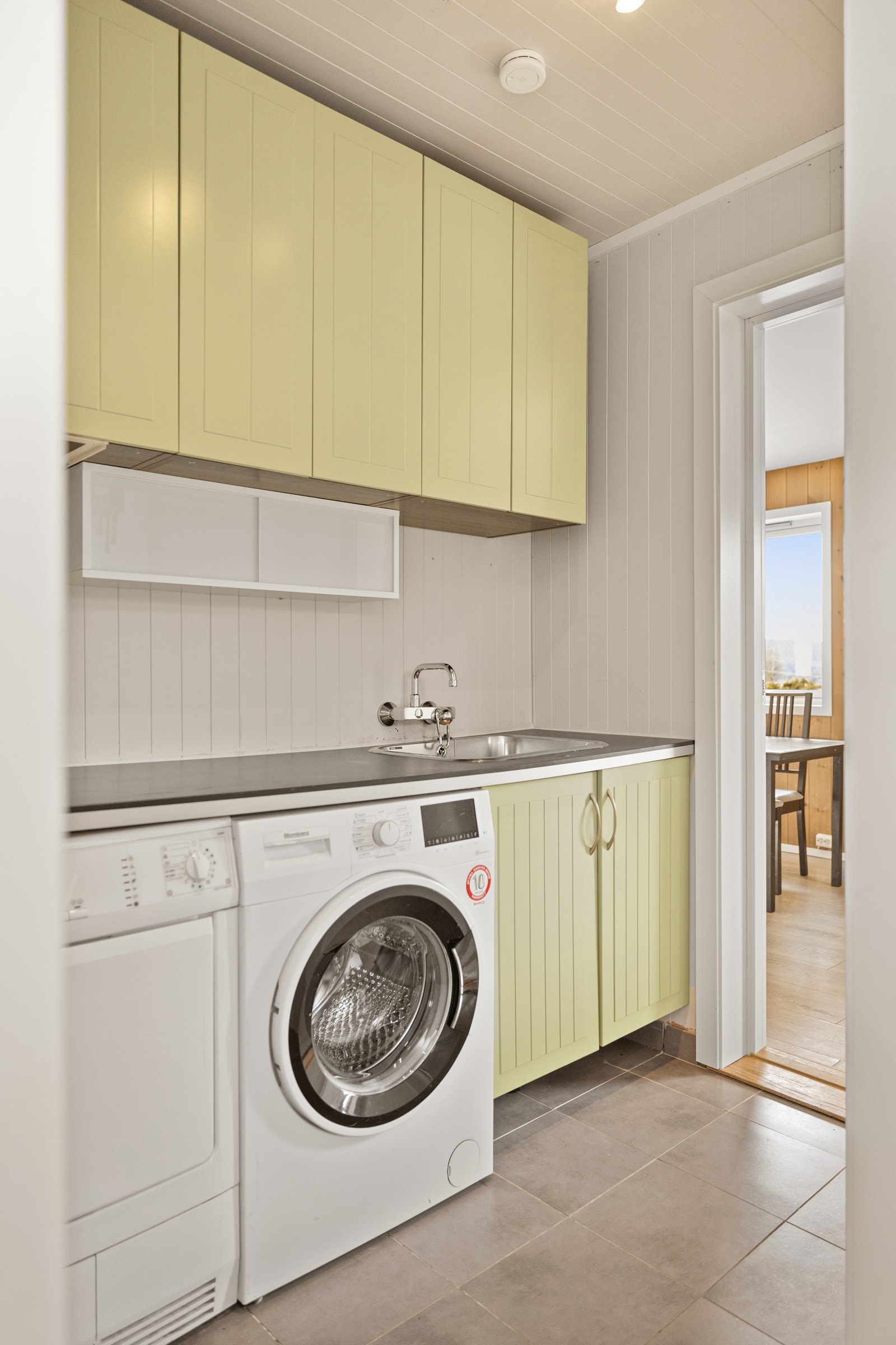 Praktisk vaskerom med opplegg for vaskemaskin og godt med oppbevaringsplass. Galleribilde